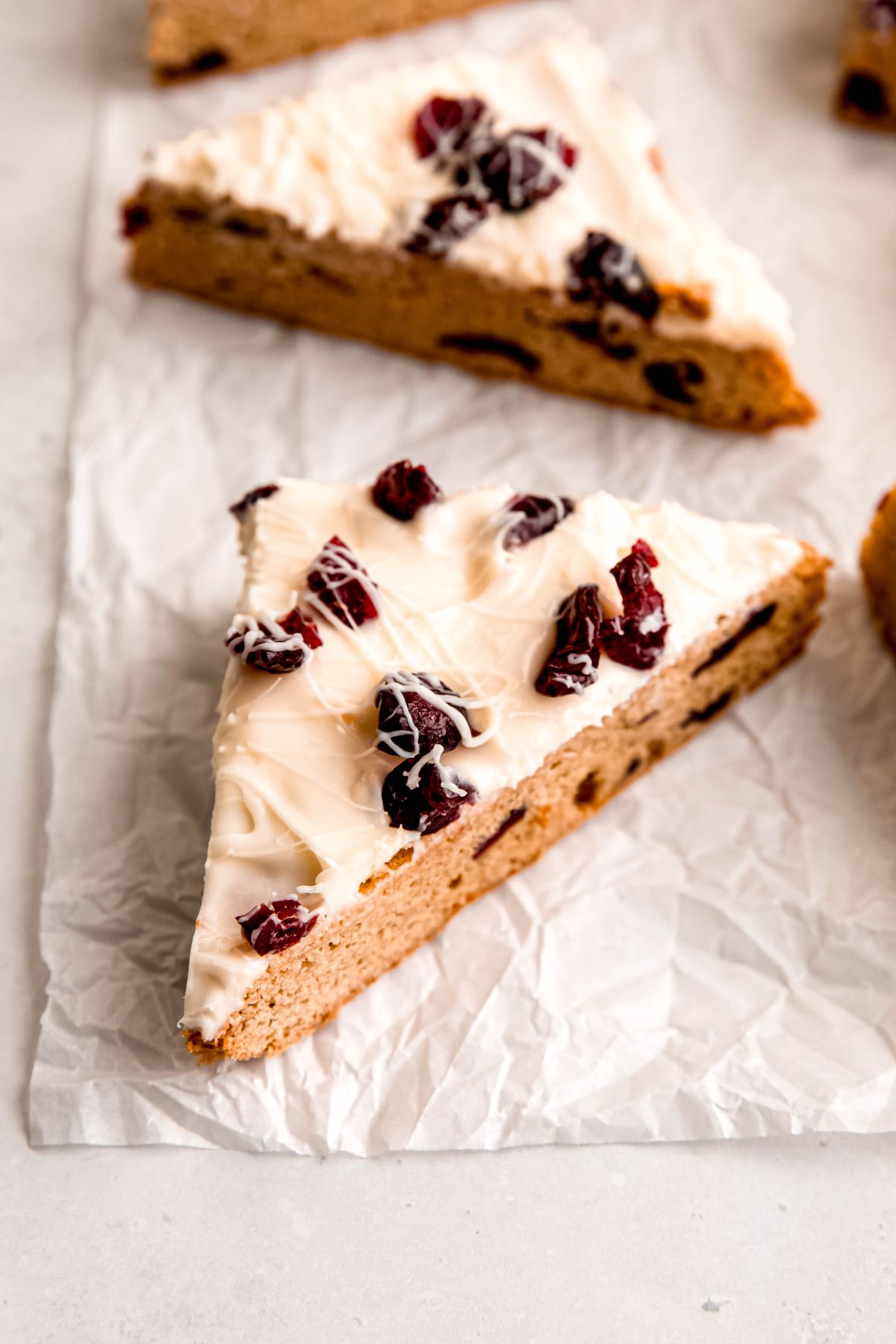 closeup shot of a homemade cranberry bliss bar on a crumpled piece of white parchment paper.