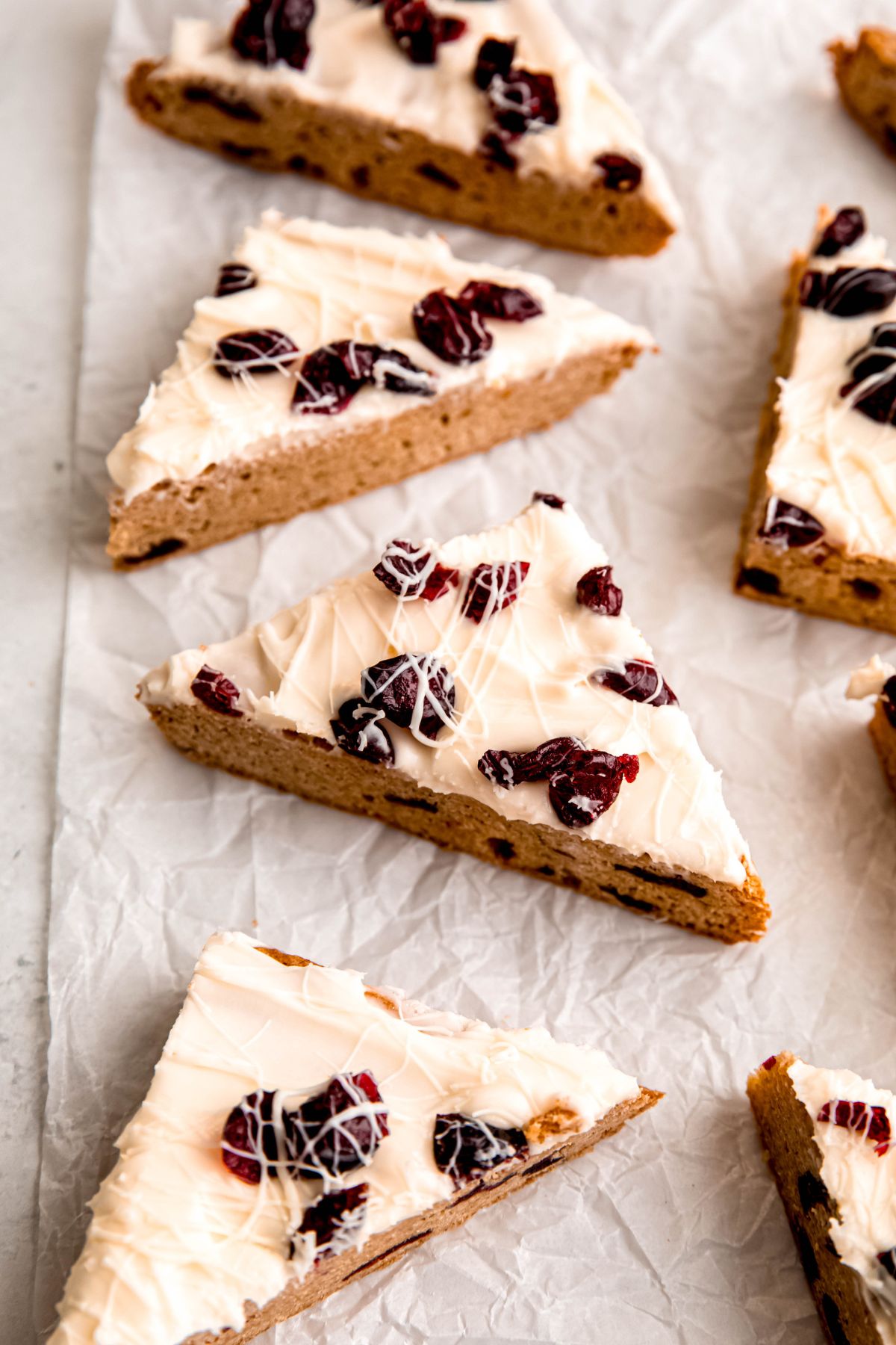 homemade starbucks cranberry bliss bars on a crumpled piece of white parchment paper with the triangles facing every which way.