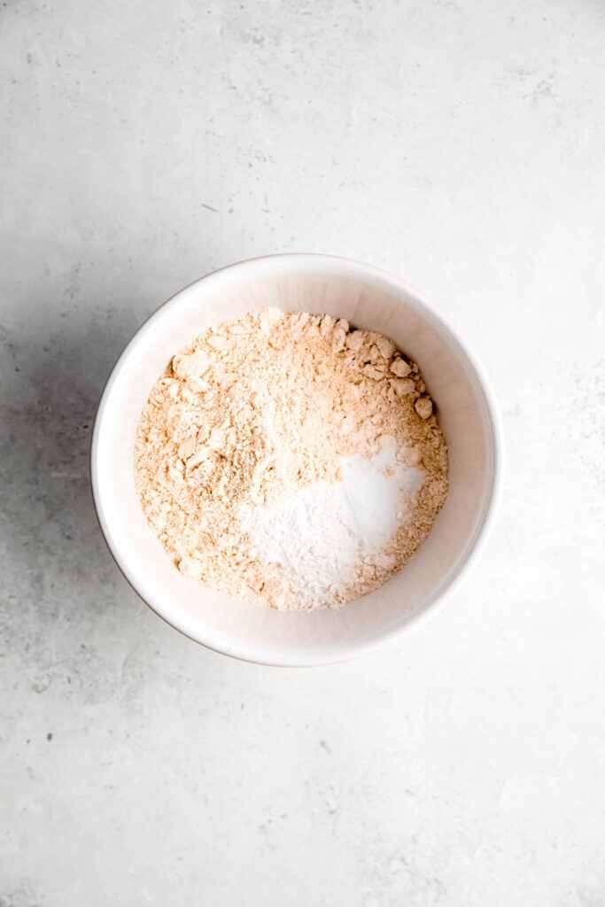 dry protein muffin ingredients added to a mixing bowl.