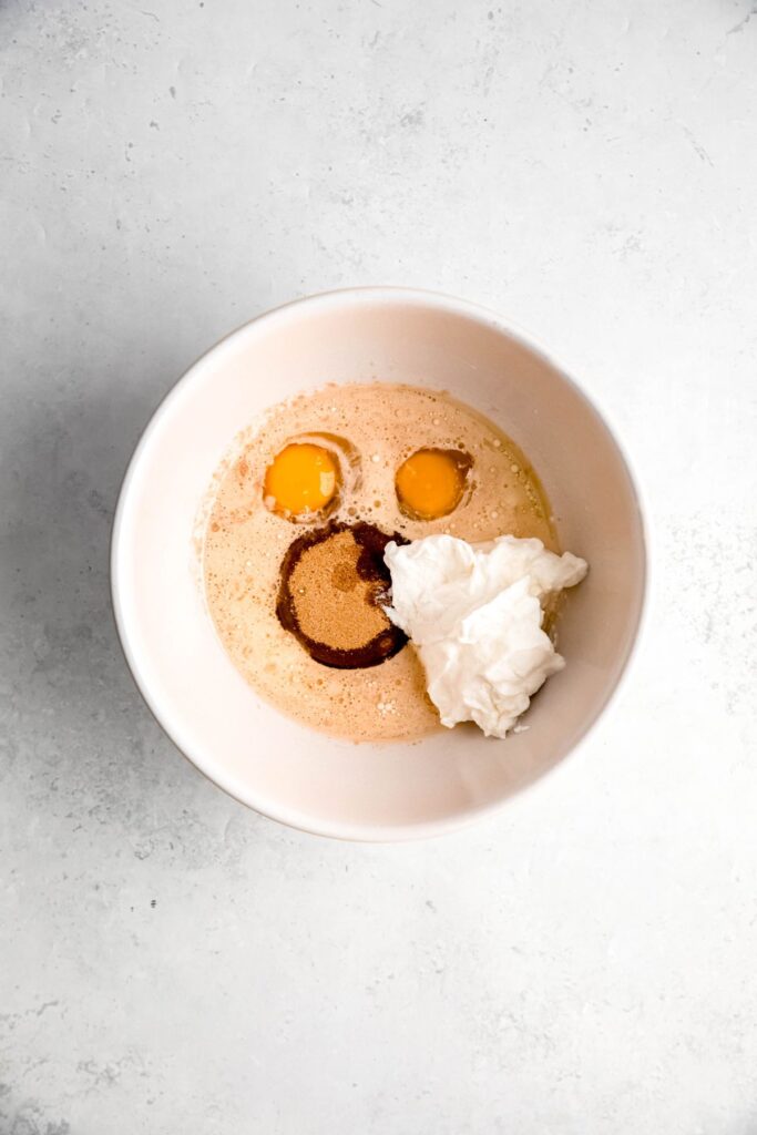 greek yogurt, sugar, milk, eggs, and vanilla extract in a separate white mixing bowl.