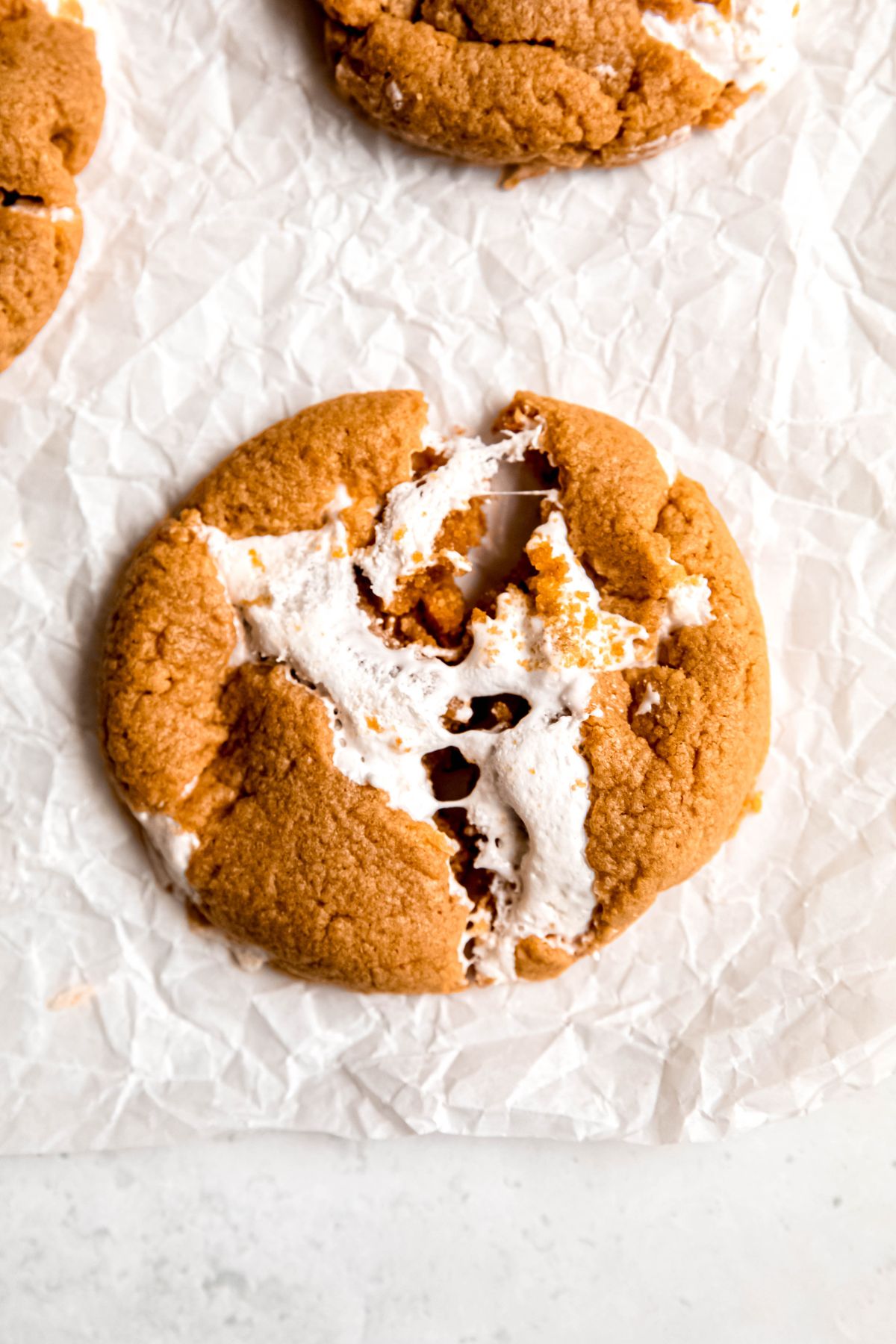 closeup shot of a homemade fluffernutter cookie that is pulled apart a smidge so you can see the melty marshmallow fluff.
