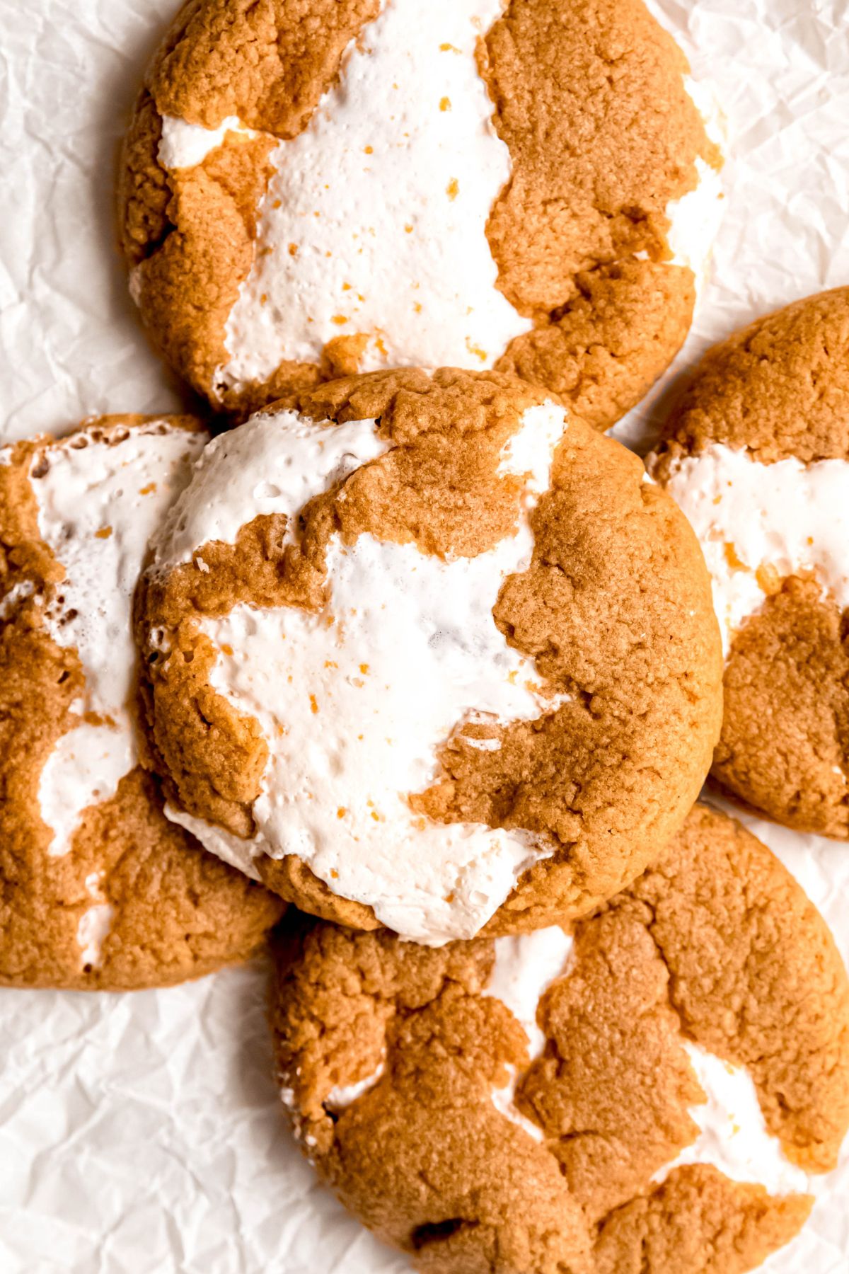 closeup overhead shot of a jumble of homemade fluffernutter cookies on a crumpled piece of white parchment paper.