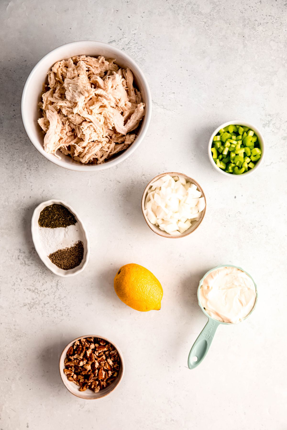 ingredients needed to make turkey salad sandwich filling with leftover turkey measured out on a white table.