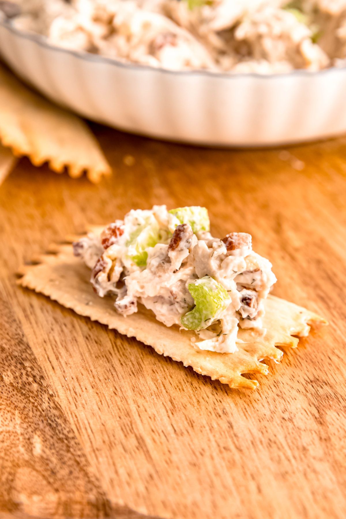 closeup shot of a scoop of leftover turkey salad on a thin cracker on a wooden board.