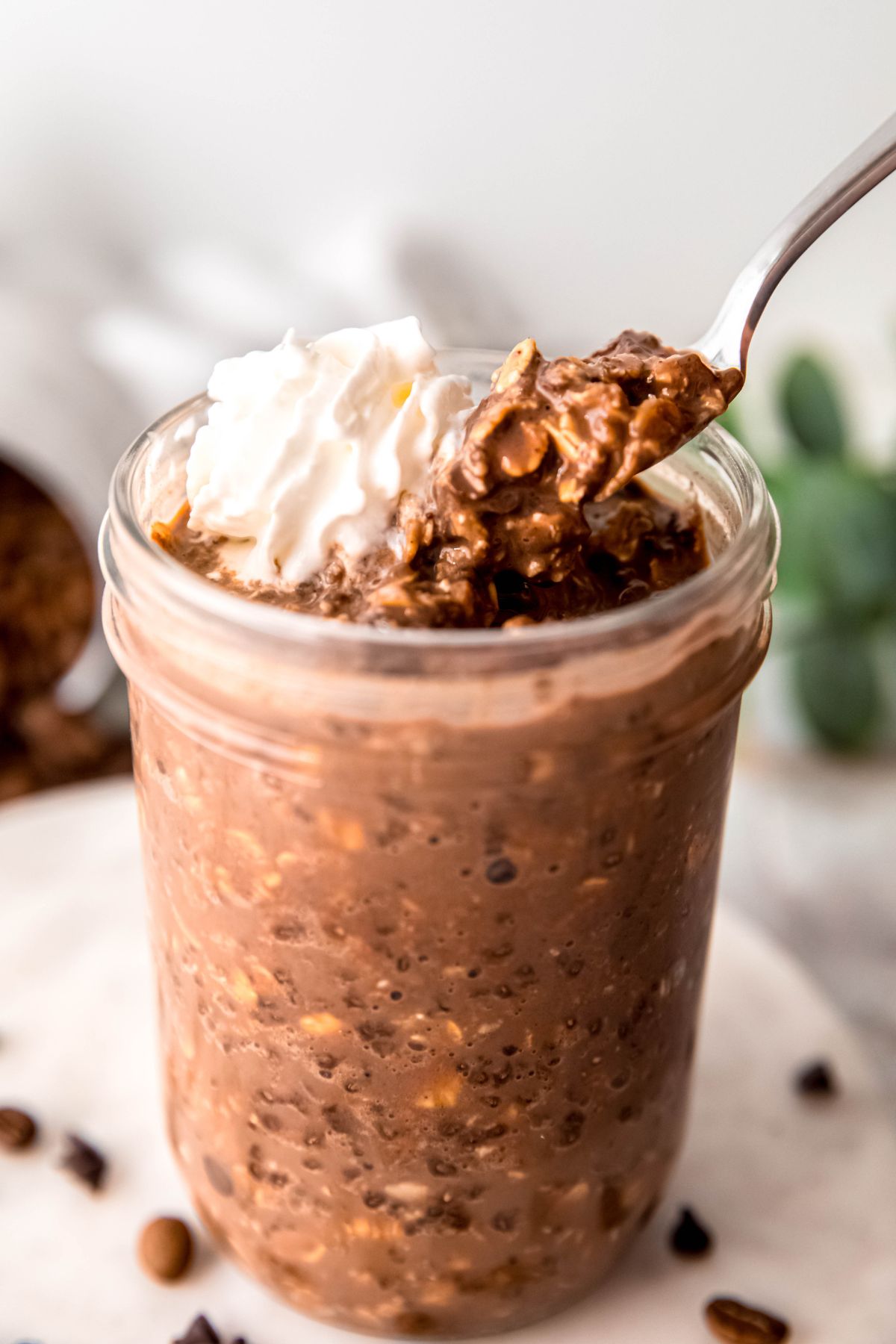 silver spoon taking a bite from the jar of mocha overnight oats showing their hearty texture.