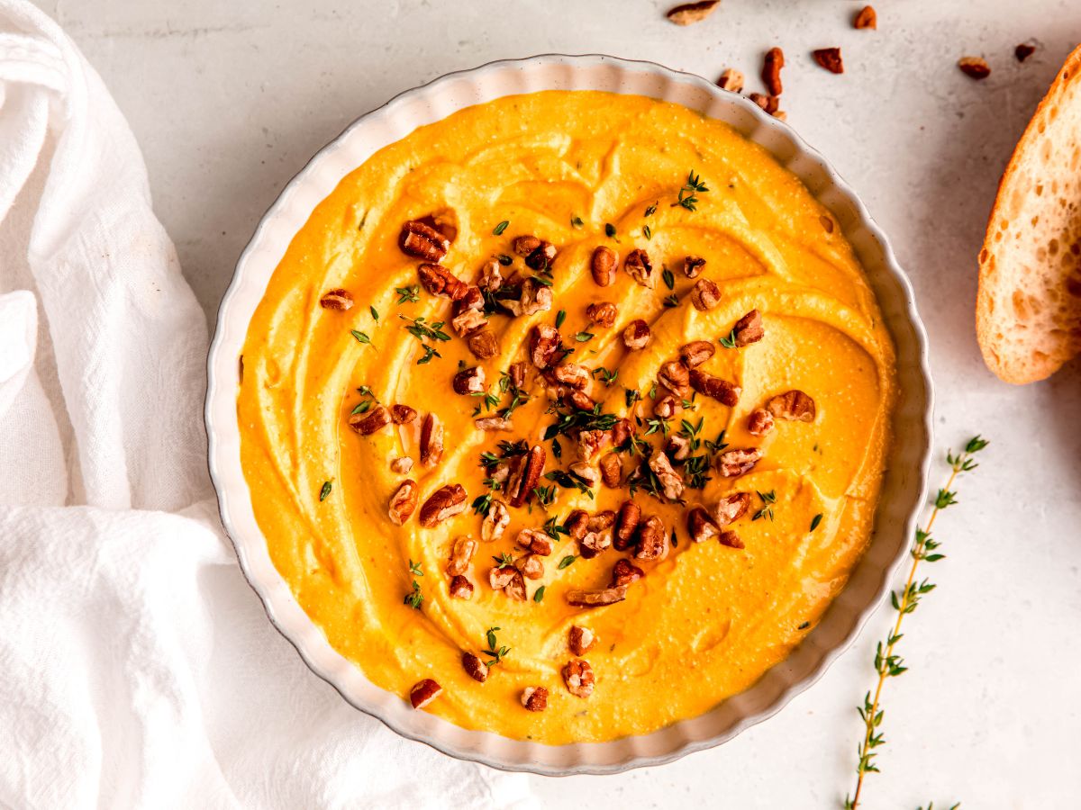 A horizontal shot of a serving bowl of pumpkin whipped feta with nuts and herbs.