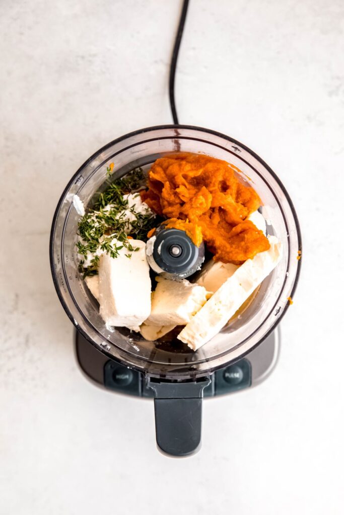 An overhead shot of a food processor with the feta, cream cheese, pumpkin, and other whipped pumpkin feta ingredients.
