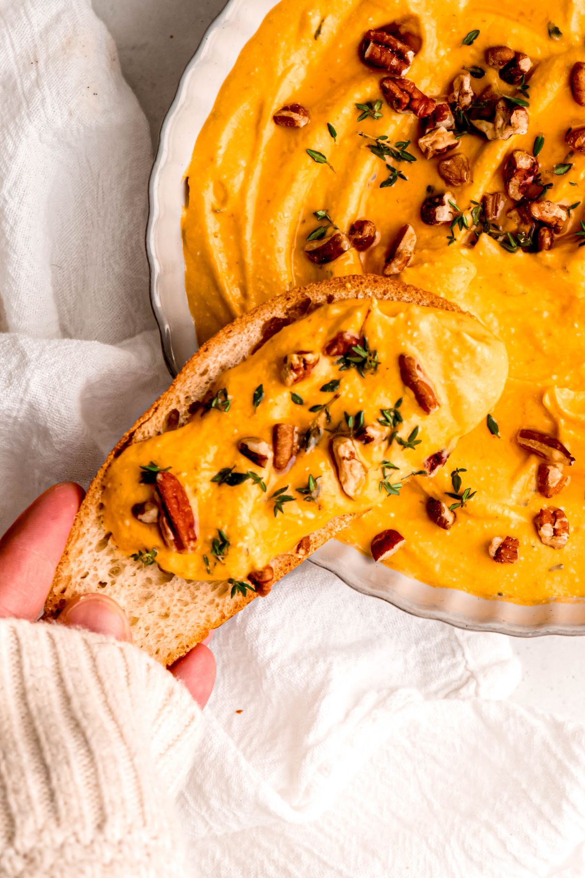 Pumpkin whipped feta on a baguette slice with nuts and herbs.