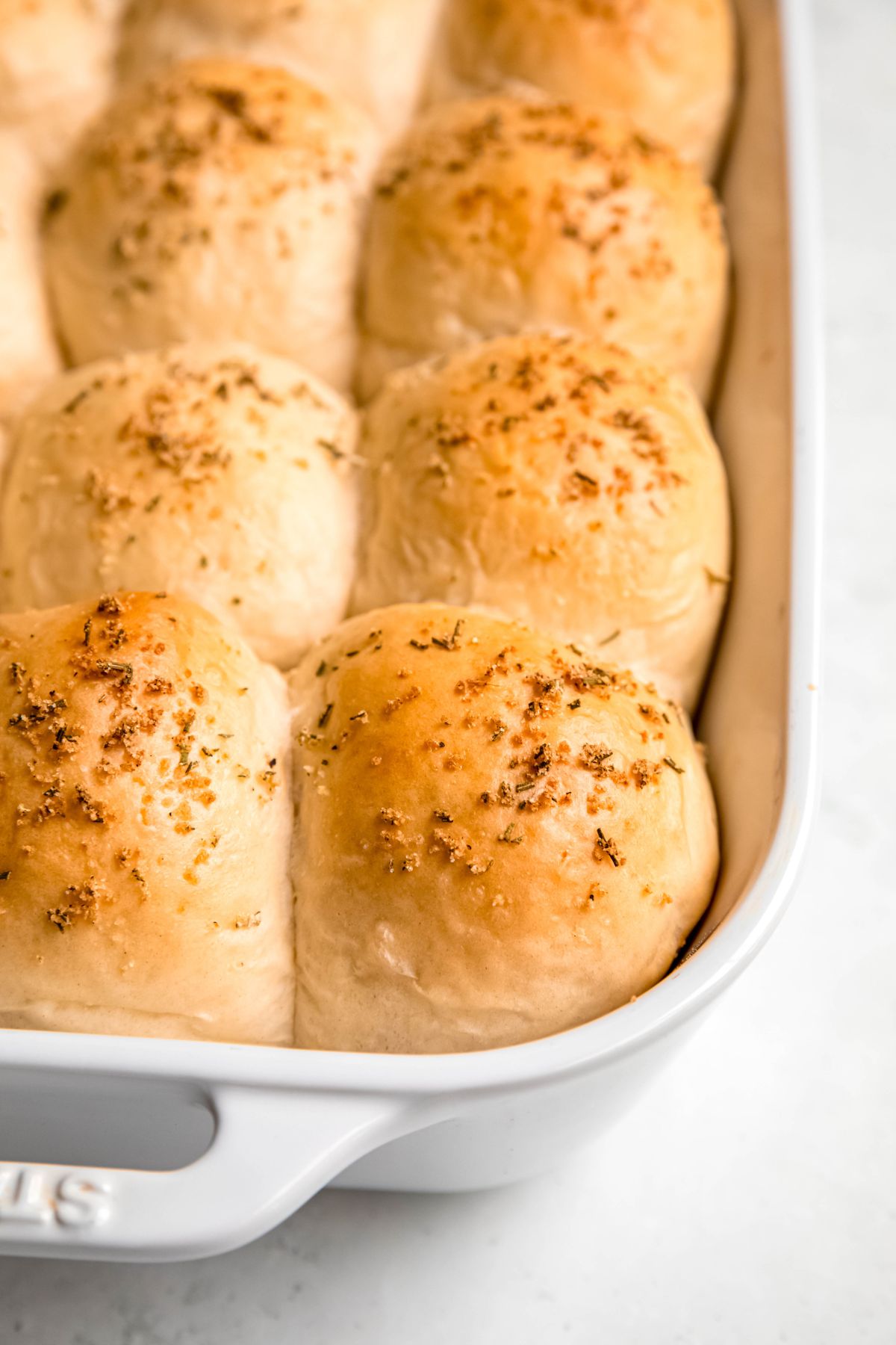 closeup on the right front corner of a tray of garlic rosemary sourdough discard dinner rolls.