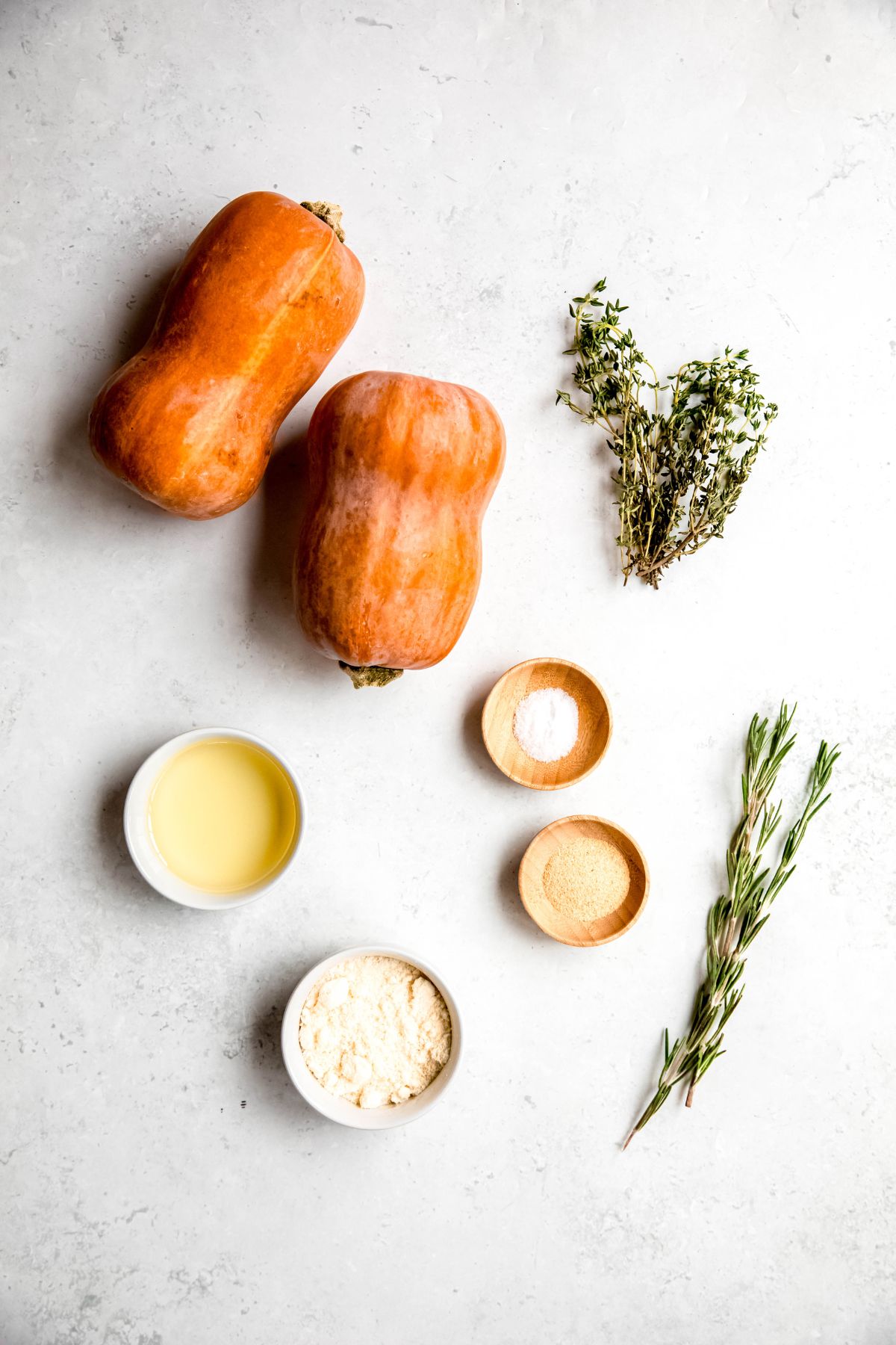 ingredients measured out for making herb and parmesan roasted honeynut squash recipe on a white table.