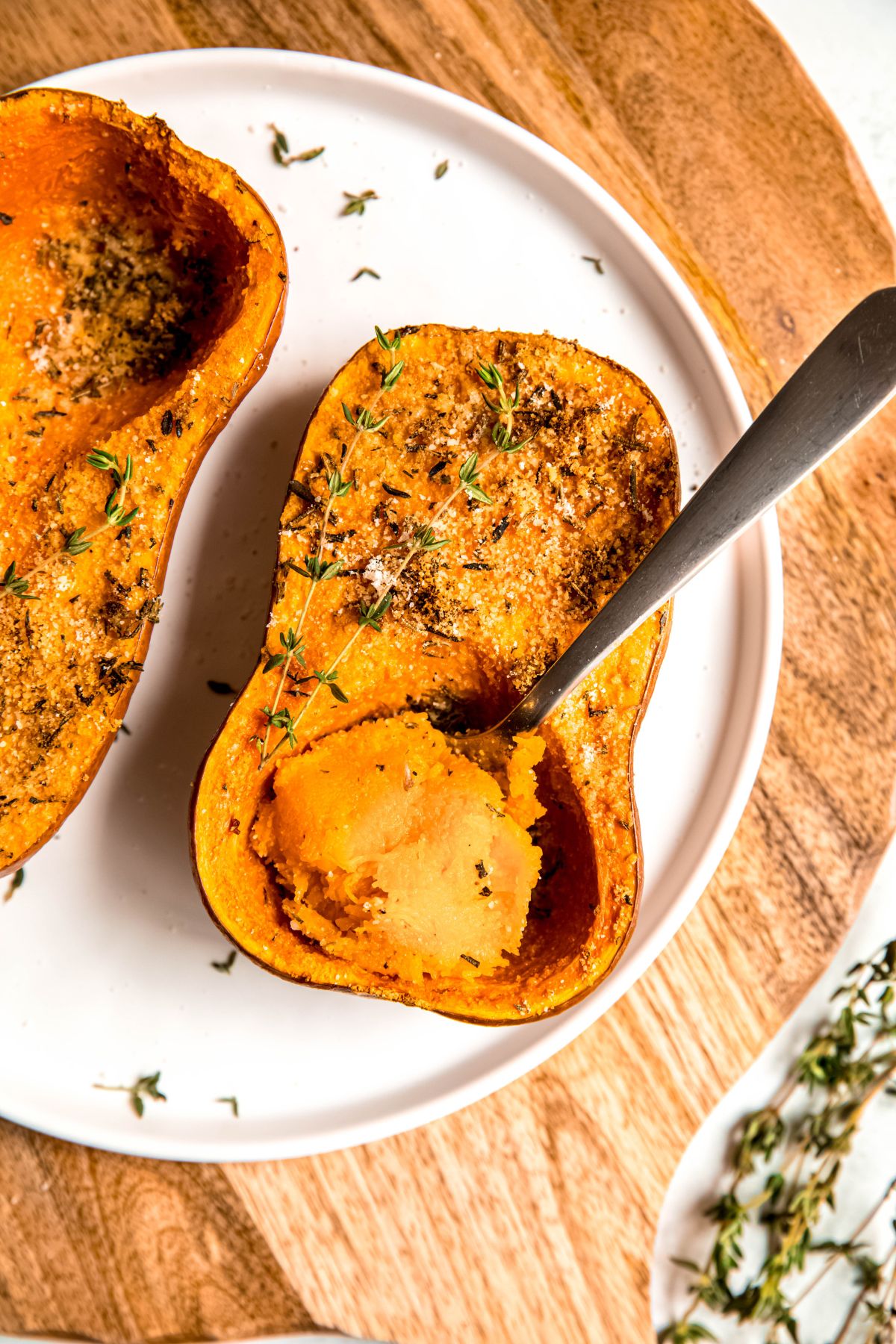 silver spoon digging out some of the tender orange flesh from the parmesan and herb roasted honeynut squash half.