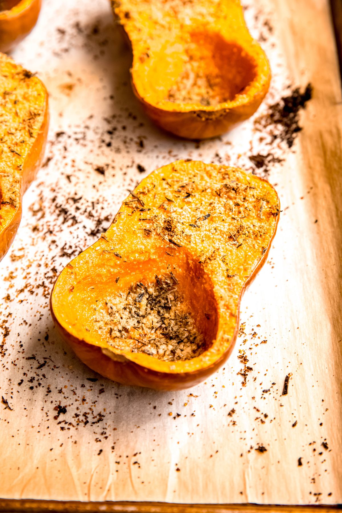 herb and parmesan roasted honeynut squash halves on a roasting sheet after baking until golden brown.