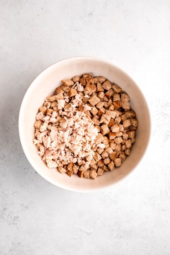 cubed bread, shredded turkey, and broth in a large mixing bowl.