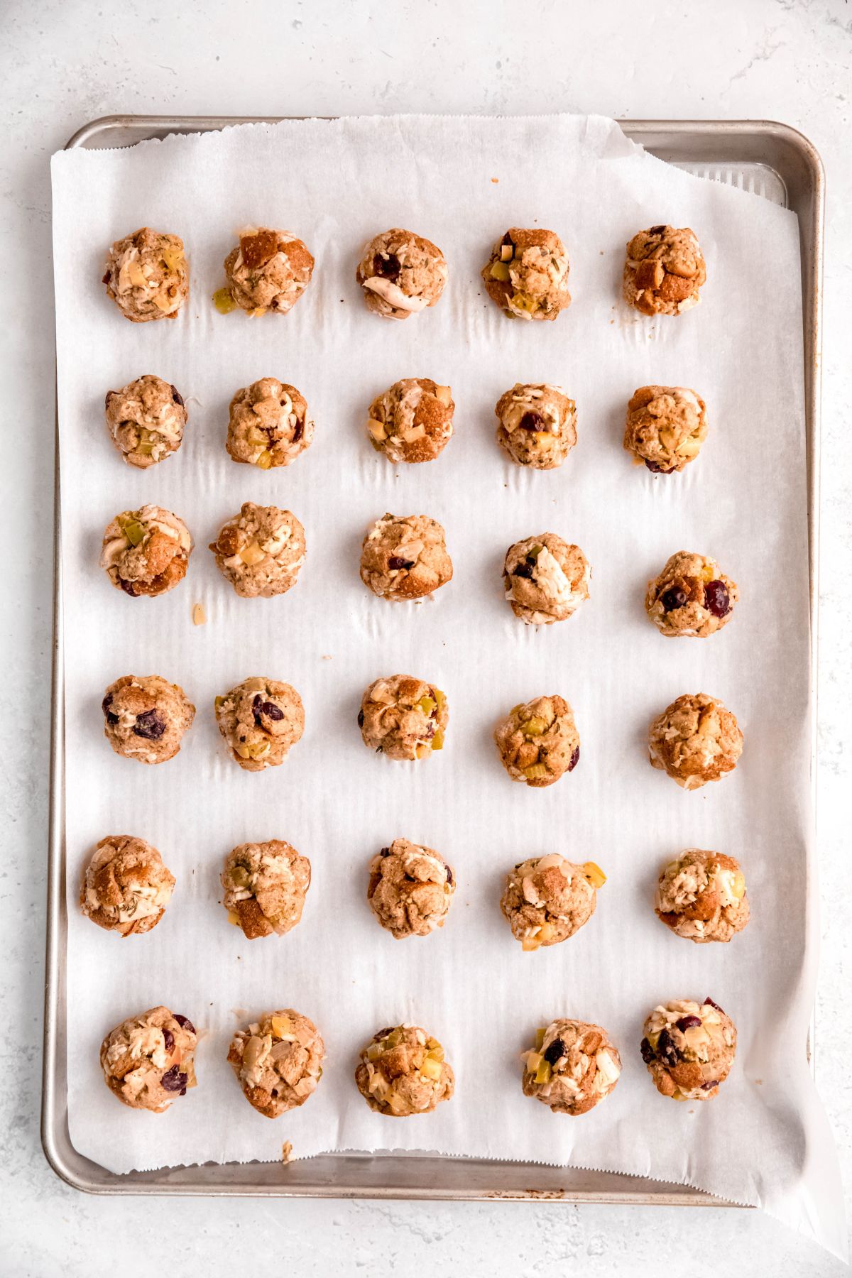 30 turkey stuffing balls on a parchment lined baking sheet prior to baking.