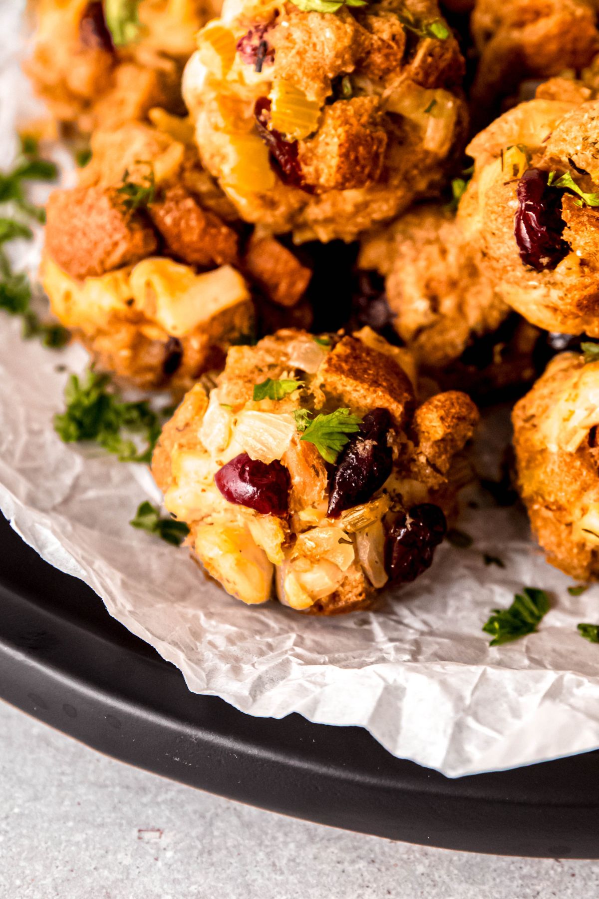 closeup shot of a serving plate of cranberry turkey stuffing balls garnished with fresh parsley.