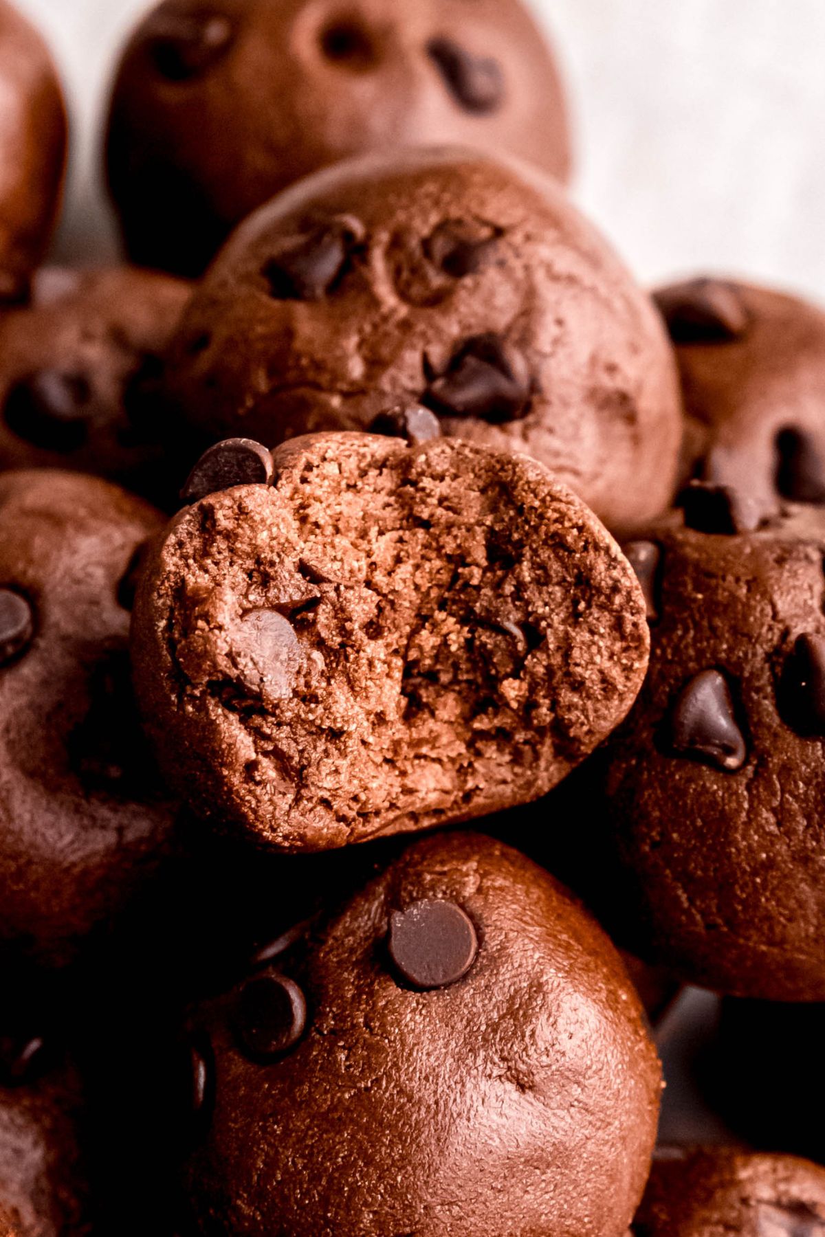 closeup shot of a chocolate protein ball with a bite taken out to show the fudgy interior.