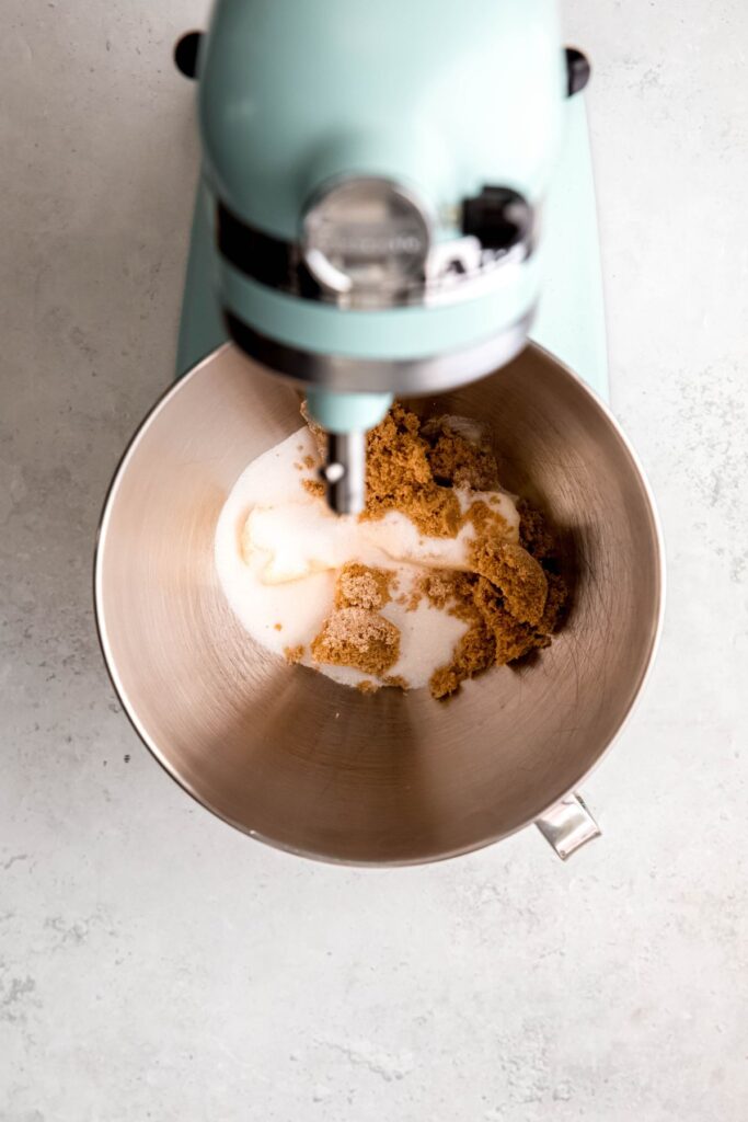 butter, sugar, and brown sugar added to the mixing bowl of a stand mixer.