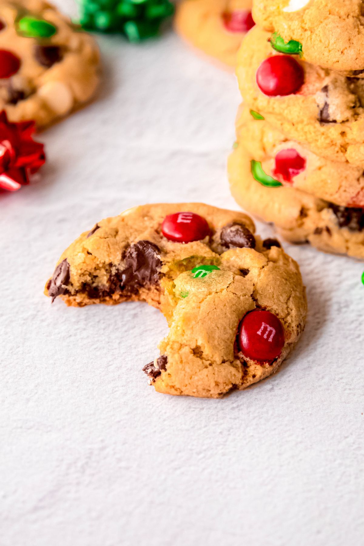 closeup shot of a Christmas chocolate chip cookie with a bite taken out to show the gooey melted chocolate and soft cookie interior.