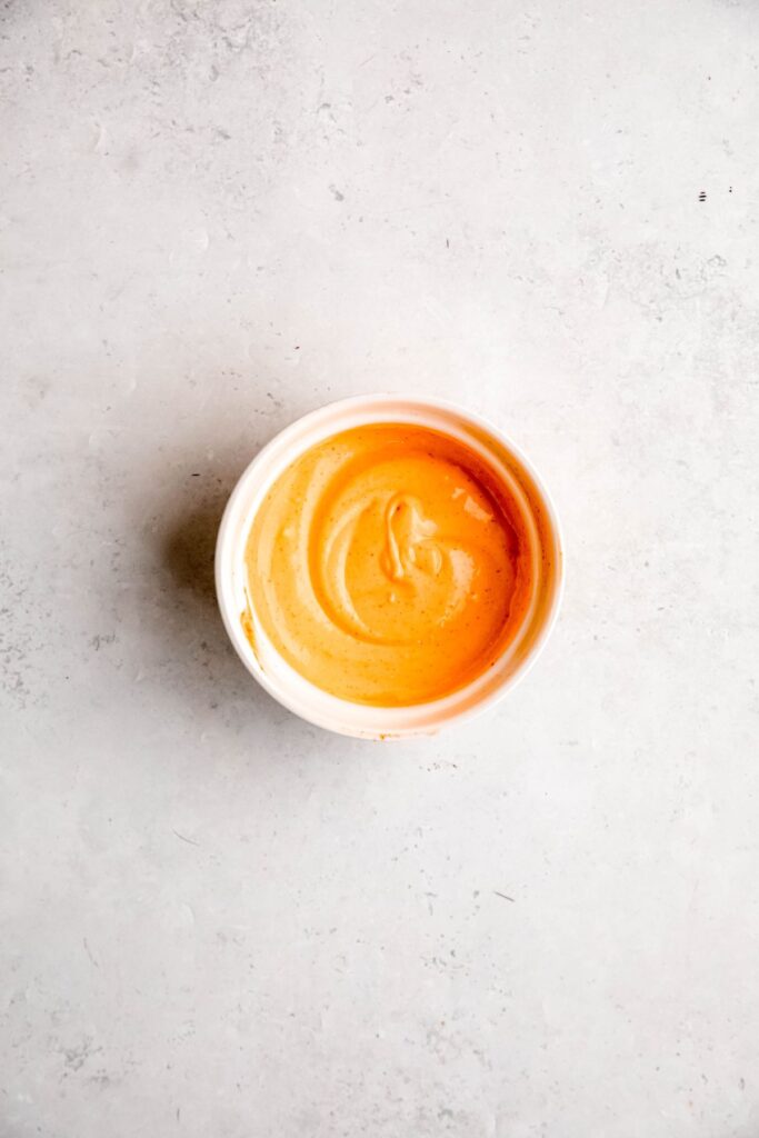An overhead shot of a small dish of spicy mayo for drizzling over the bowls.
