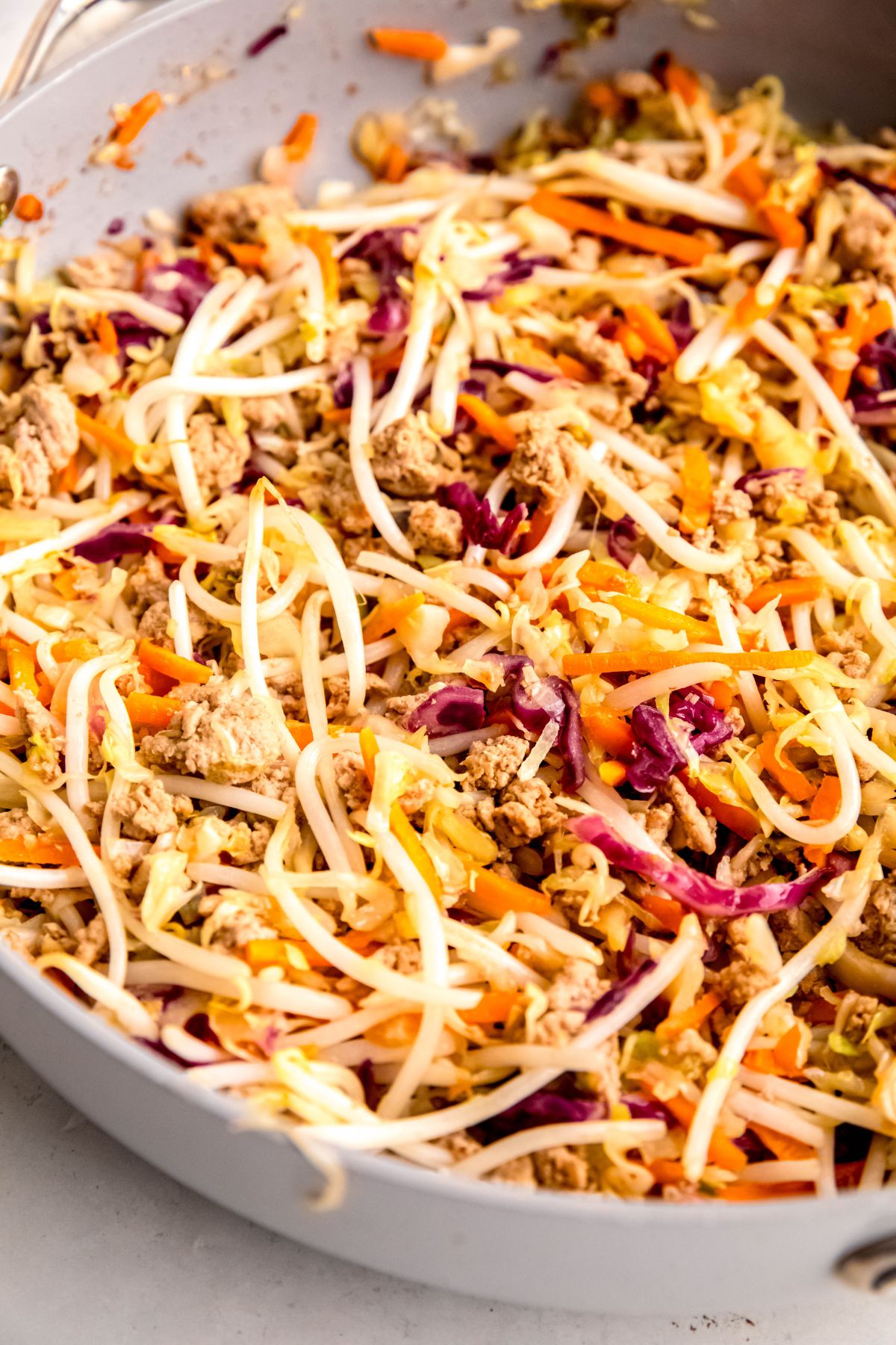 A close-up shot of the ground turkey, coleslaw mix, and bean sprouts cooking in the skillet.