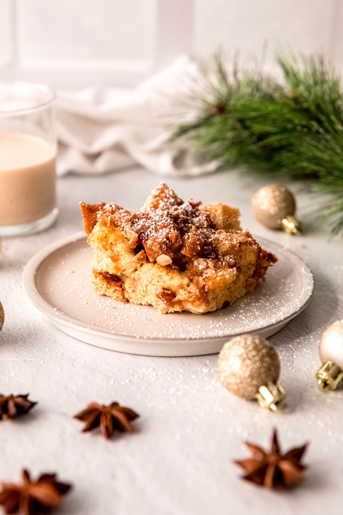 A small plate with a small serving of eggnog French toast casserole dusted with powdered sugar.