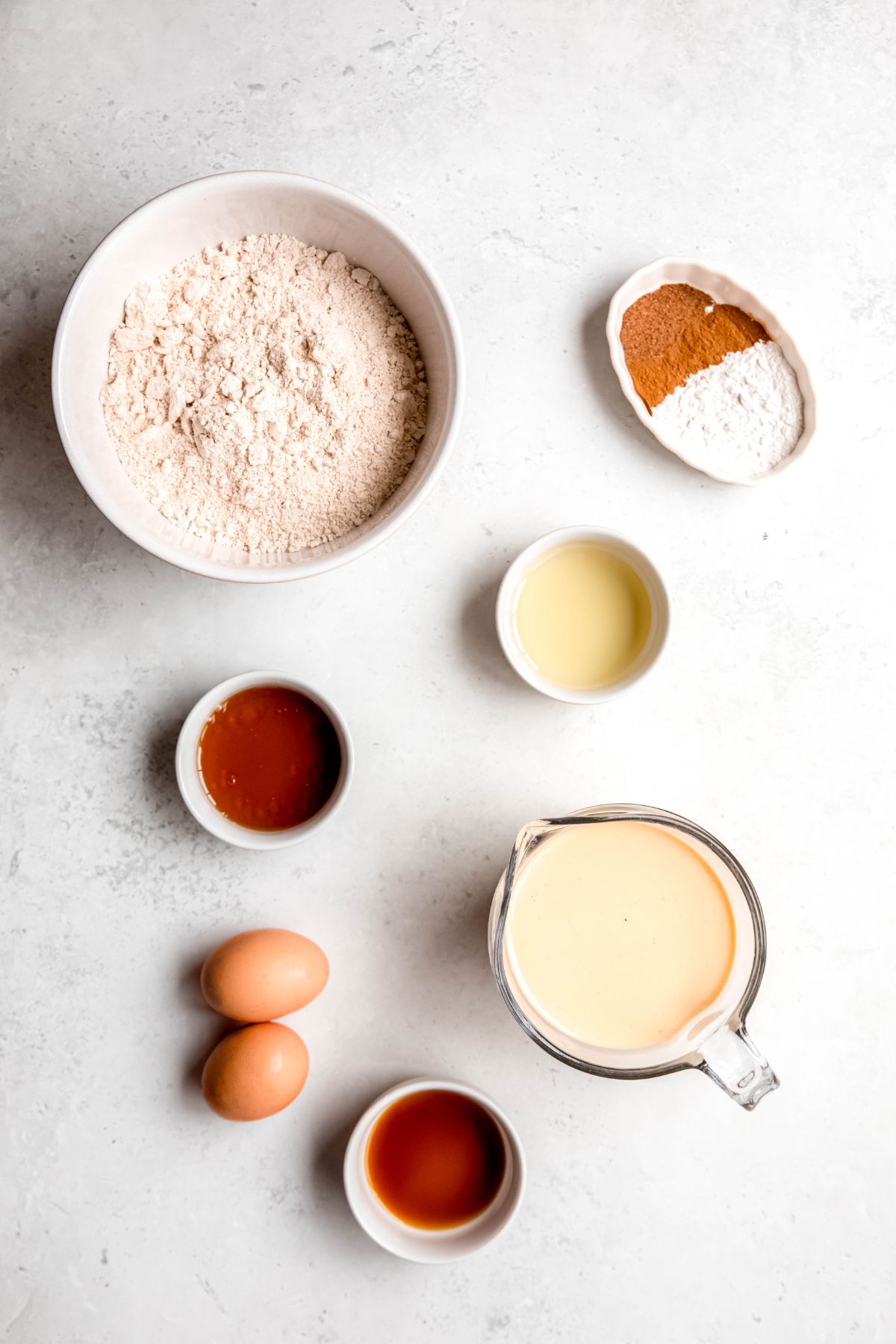 ingredients for making healthy homemade eggnog pancakes recipe measured out on a white table.