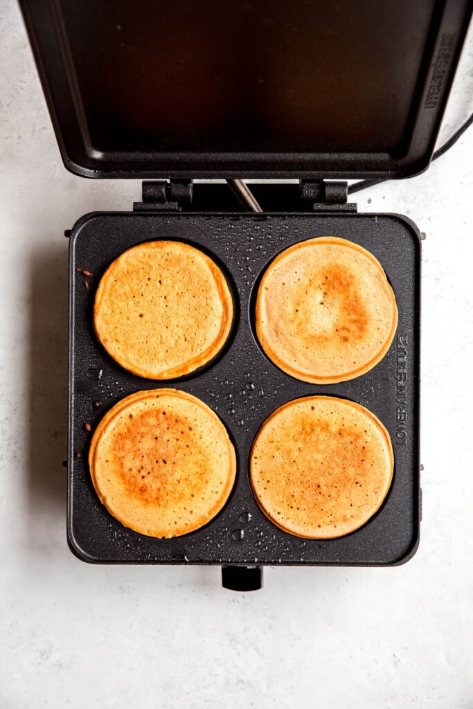square griddle with 4 eggnog pancakes after flipping; the tops are nicely golden.
