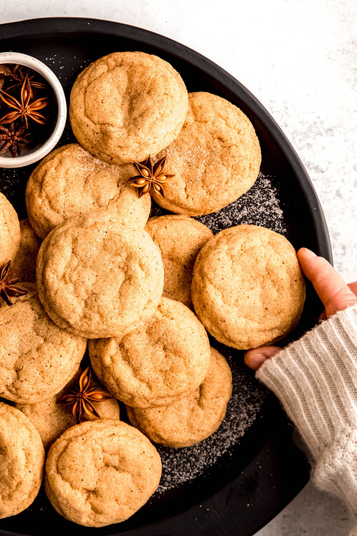 hand grabbing an eggnog snickerdoodle cookie off a serving platter.