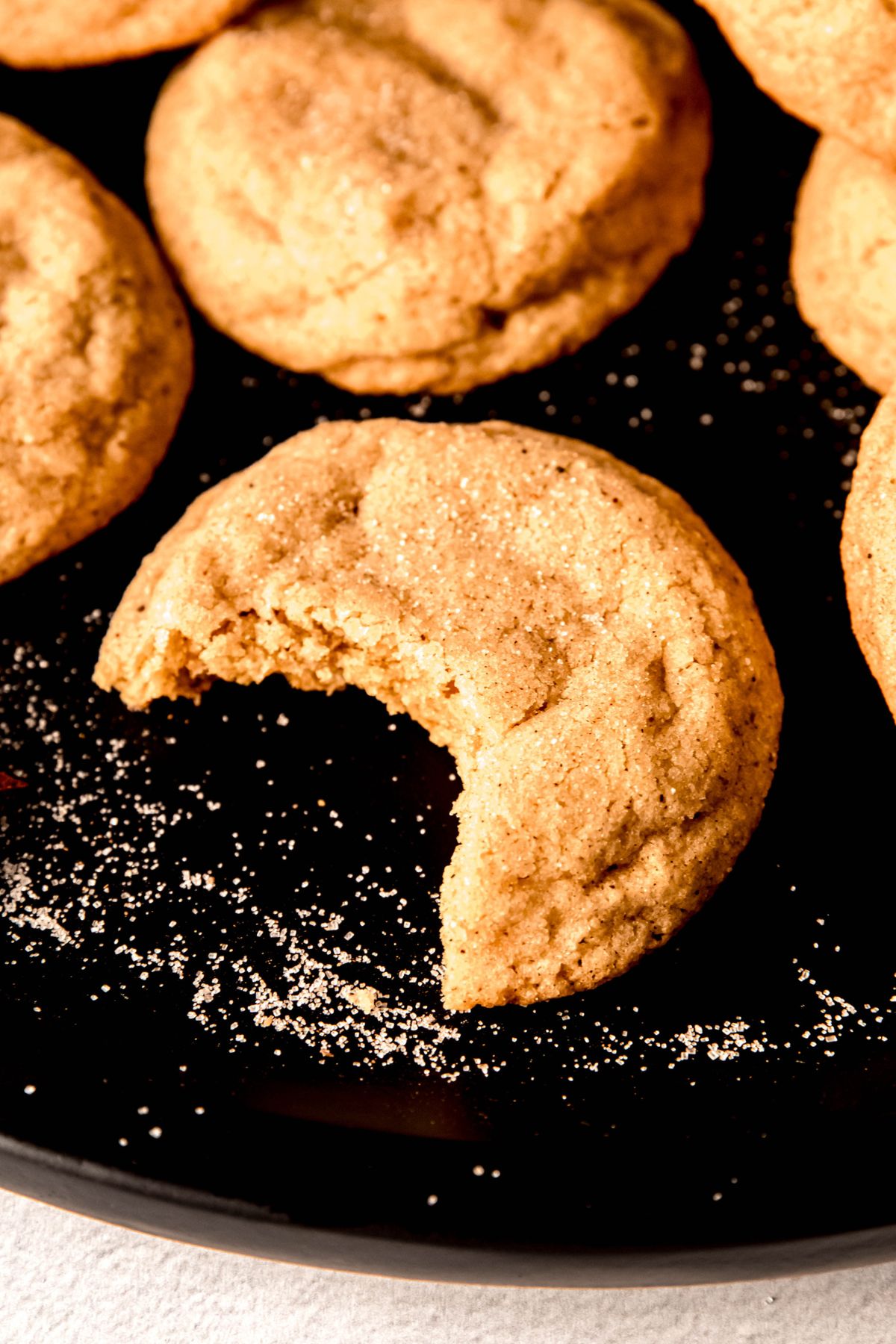closeup shot of an eggnog snickerdoodle cookie with a bite taken out showing the chewy interior.