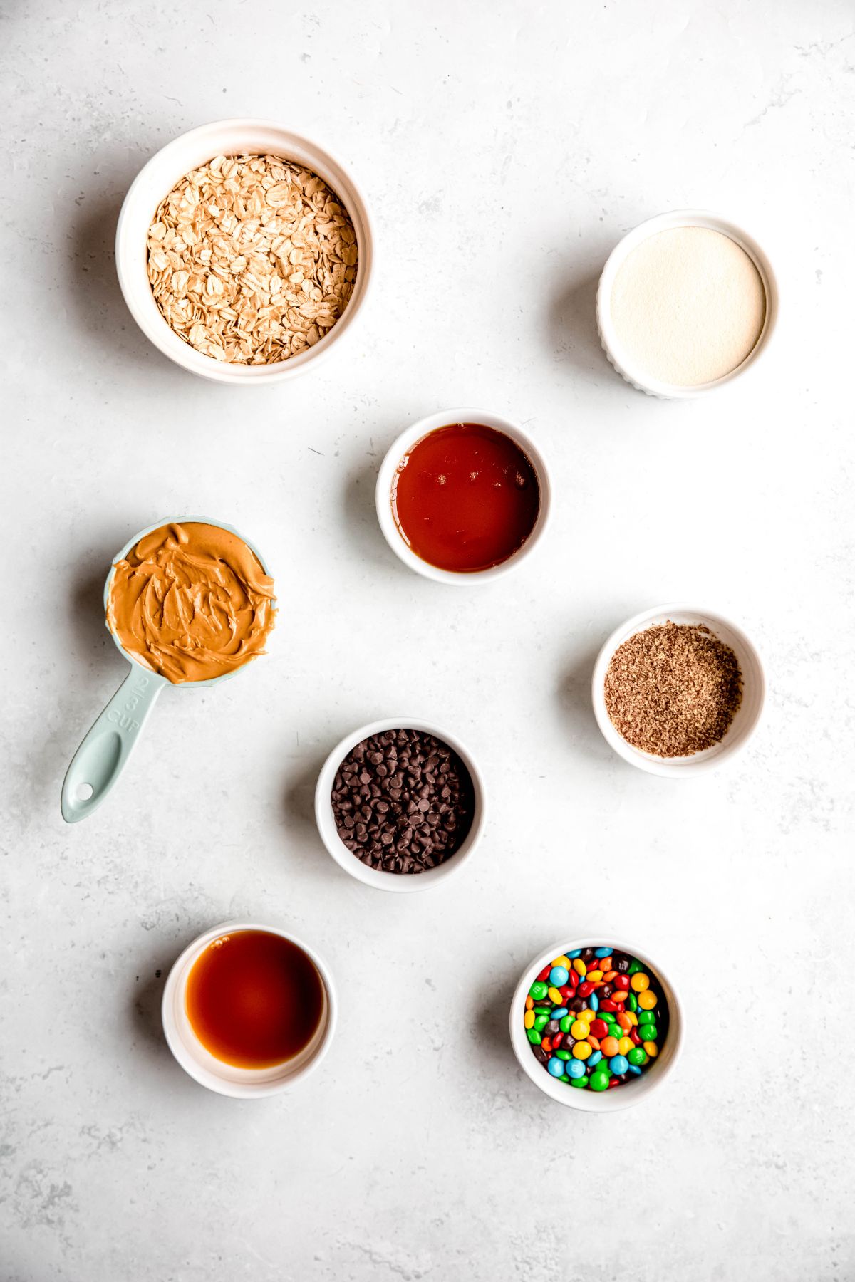 ingredients needed to make a healthy monster cookie protein ball recipe measured out on a white table.