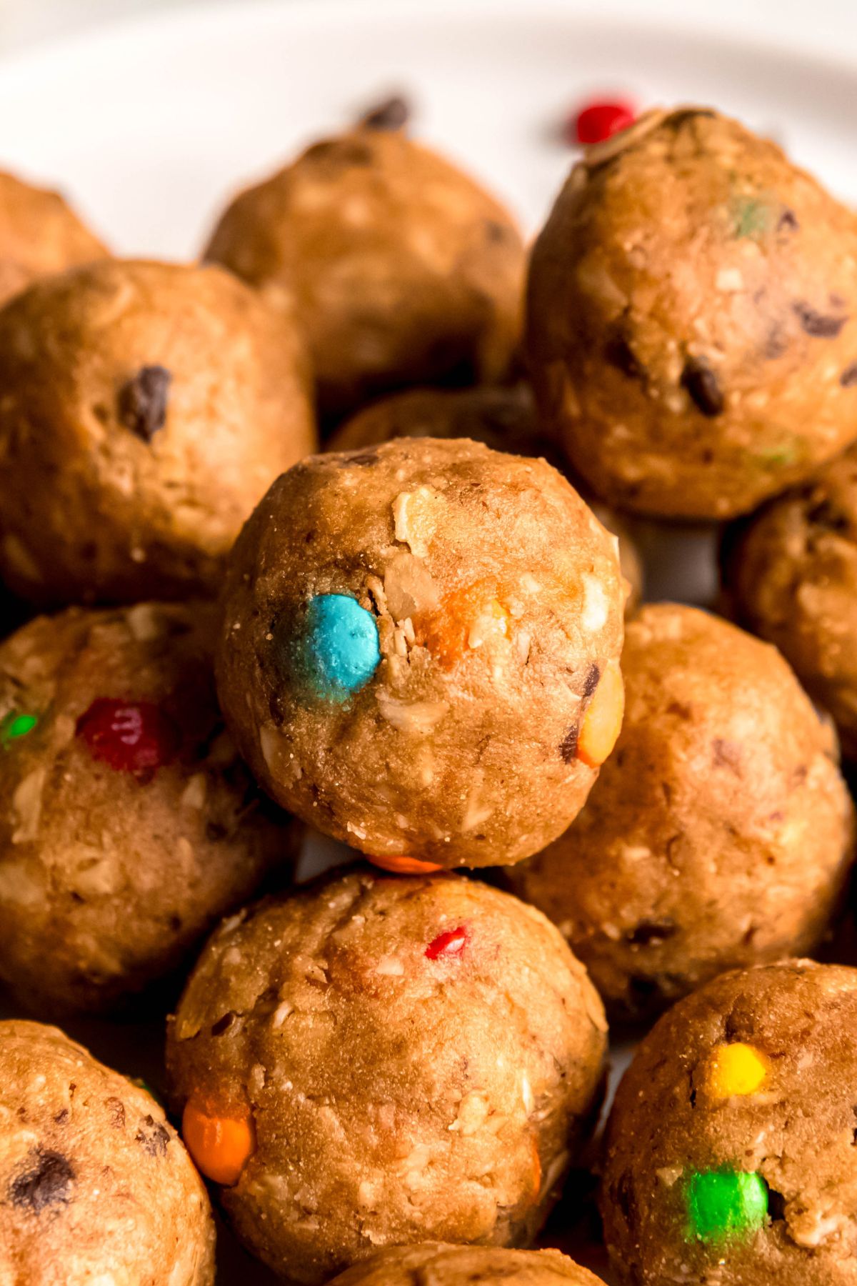 closeup shot of a pile of monster cookie protein balls showing the mini chocolate chips, M&Ms, and oats.