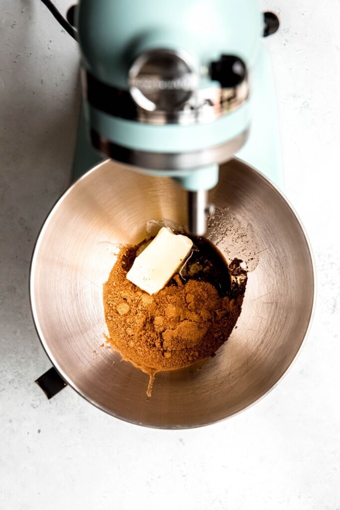 An overhead shot of a stand mixer with peanut butter, butter, and coconut sugar.