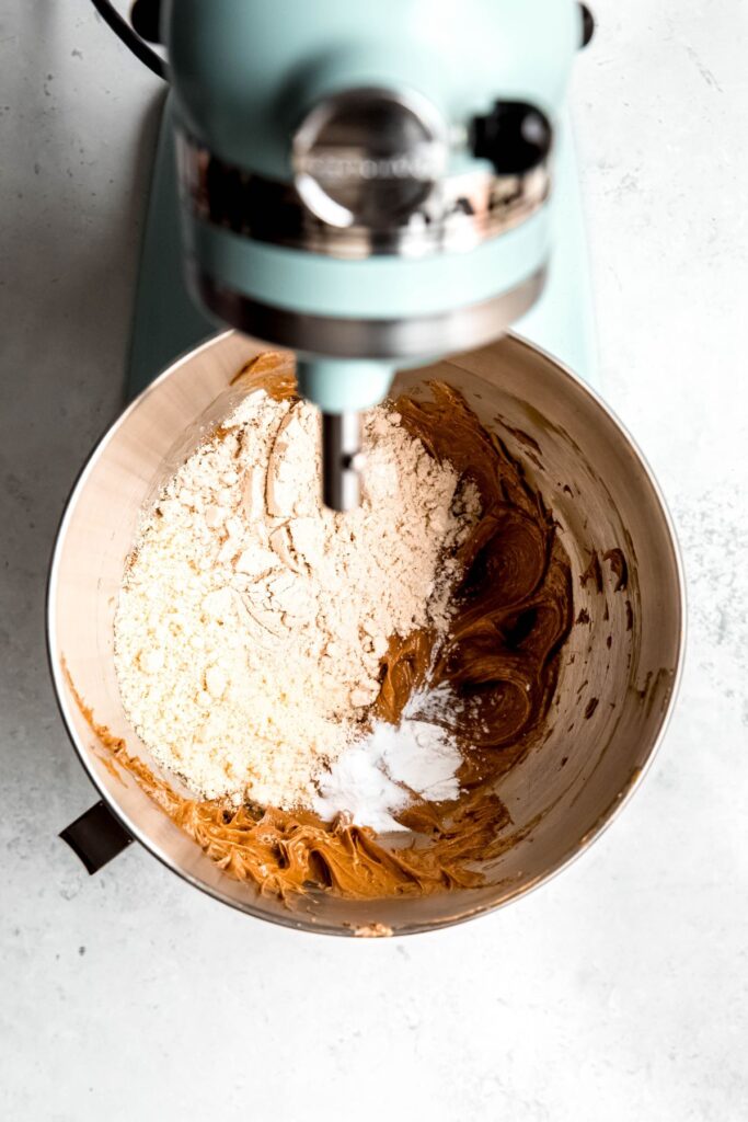 An overhead shot of a stand mixer with the peanut butter mixture, flour, and the leavening agents.