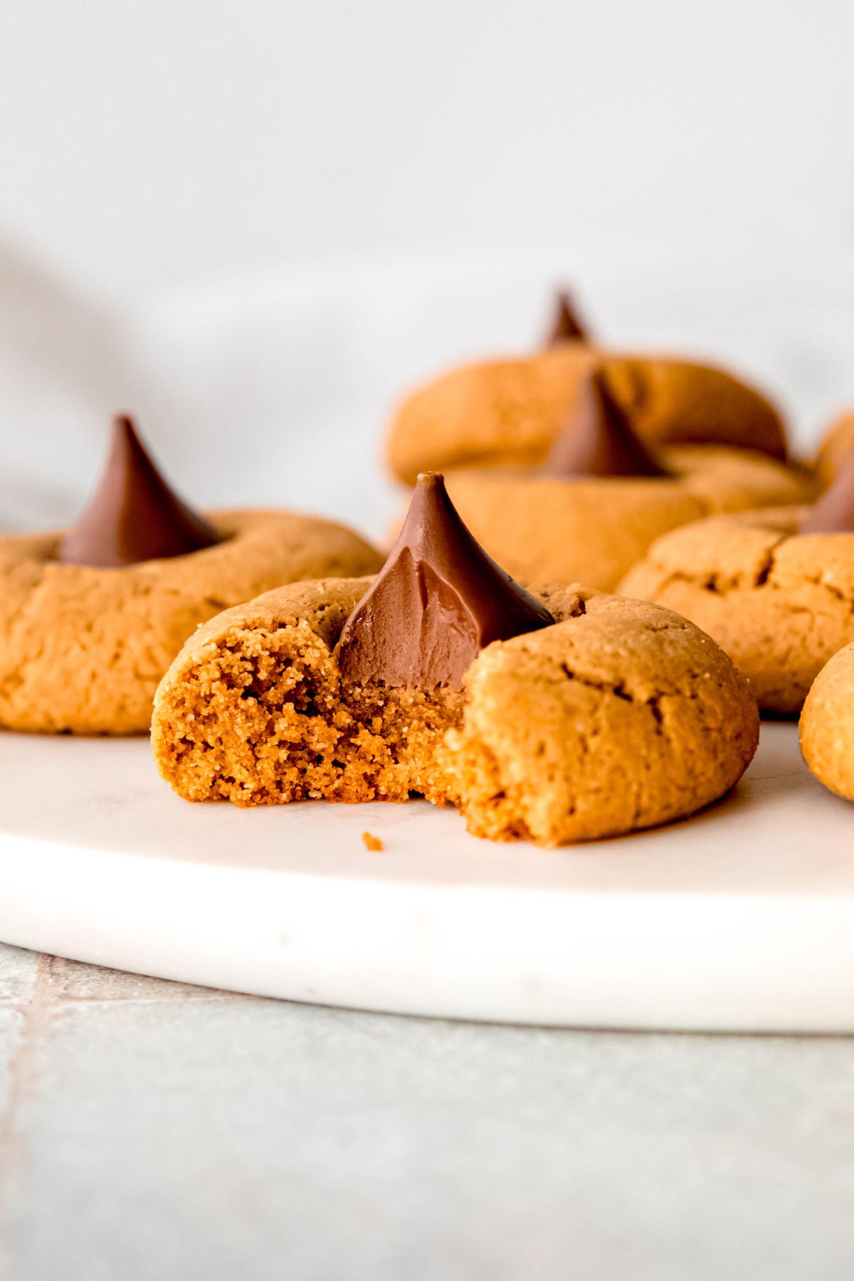 A close-up side shot of a gluten-free peanut butter blossom cookie with a bite taken out of it.