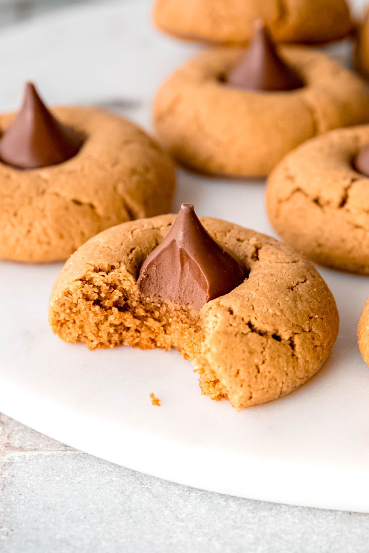 A close-up shot of gluten-free peanut butter blossoms with a bite taken out of one.