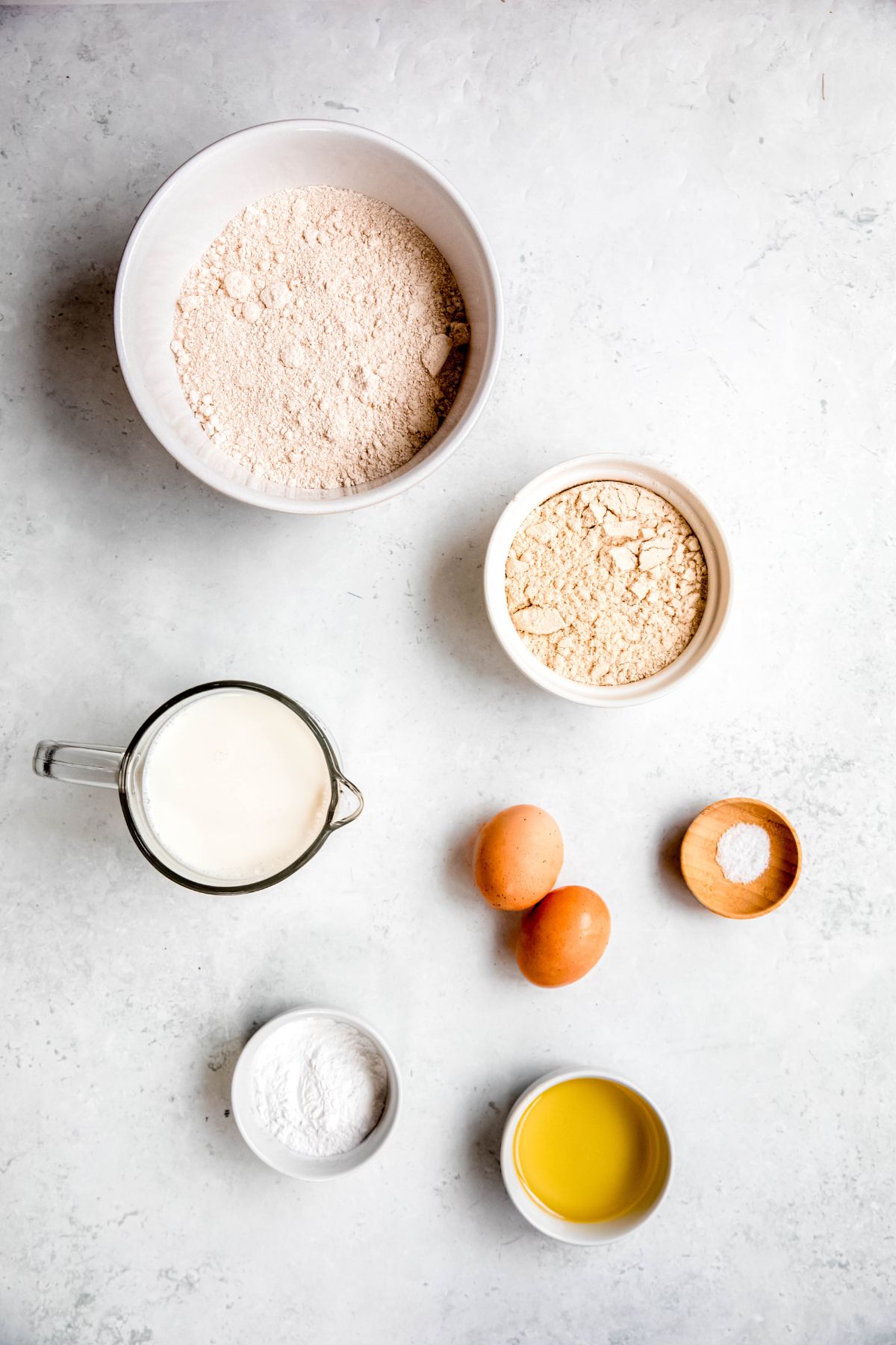 overhead shot of the ingredients needed to make whole wheat protein powder pancakes recipe measured out on a white table.