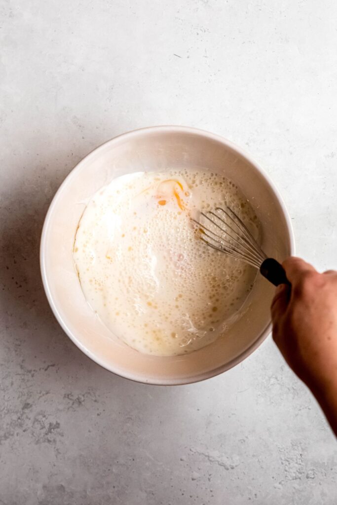 action shot of a hand whisking the wet ingredients together.