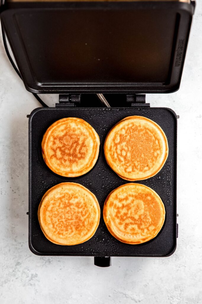 golden brown pancakes with protein powder on the griddle after flipping.