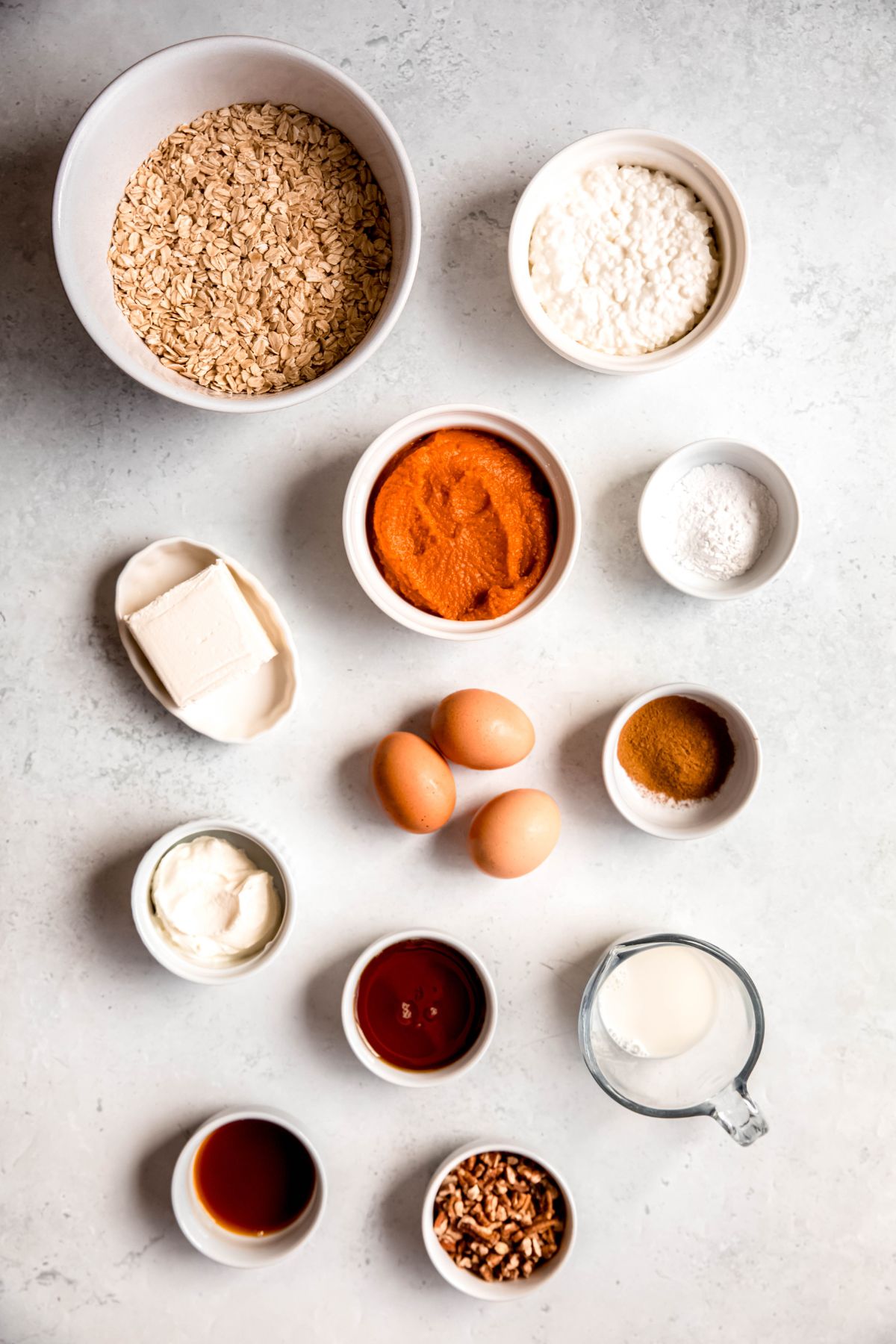 ingredients needed to make high protein baked pumpkin oatmeal recipe measured out on a white table.