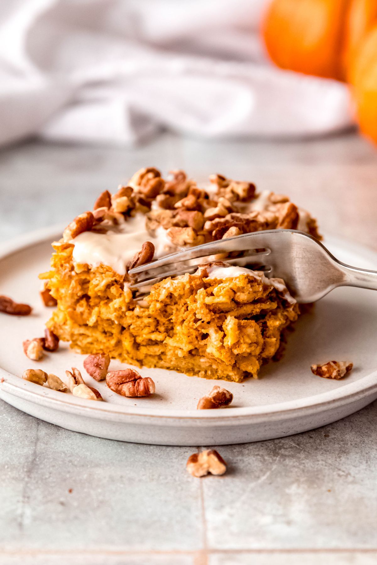 silver fork taking a bite from the corner of a slice of baked pumpkin oats showing the springy, cake like texture.