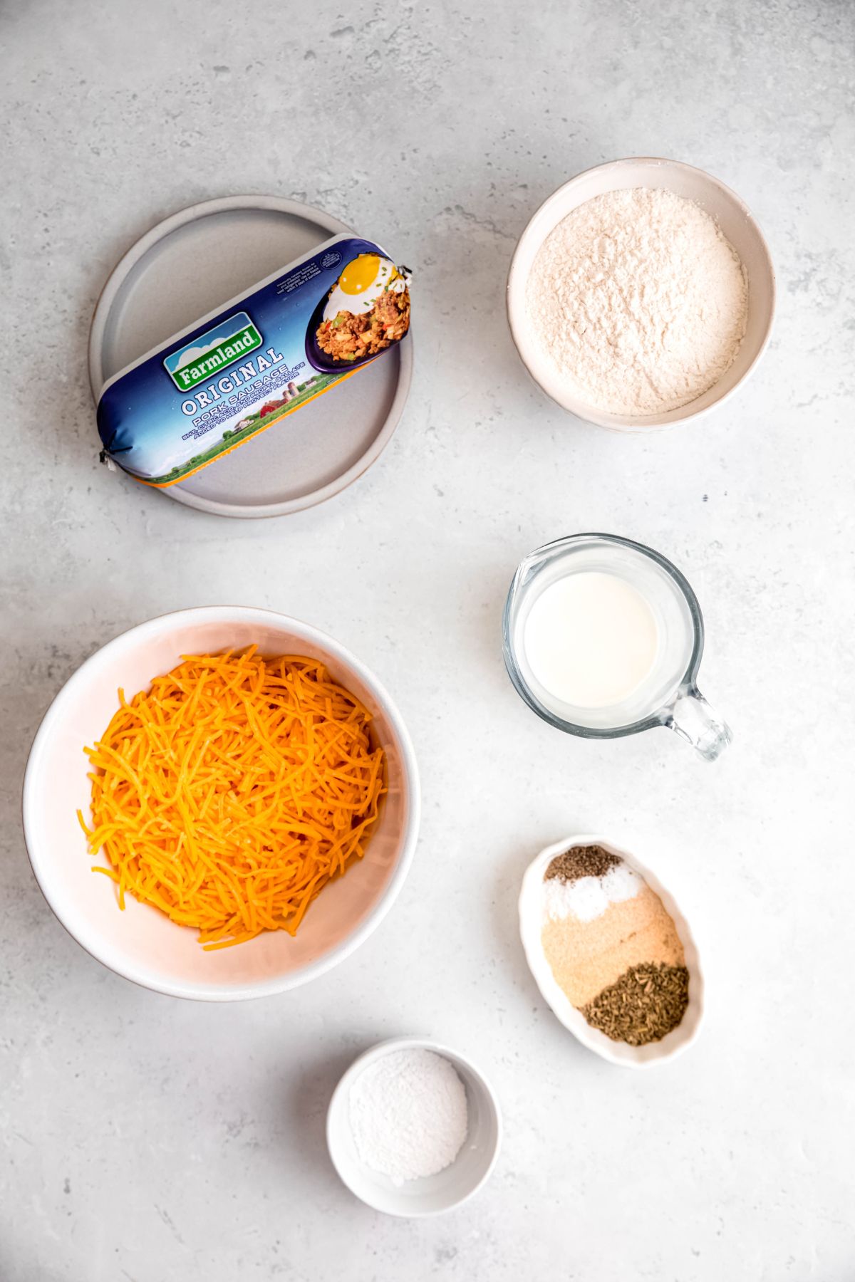 ingredients needed for making sausage balls with flour measured out on a white table.