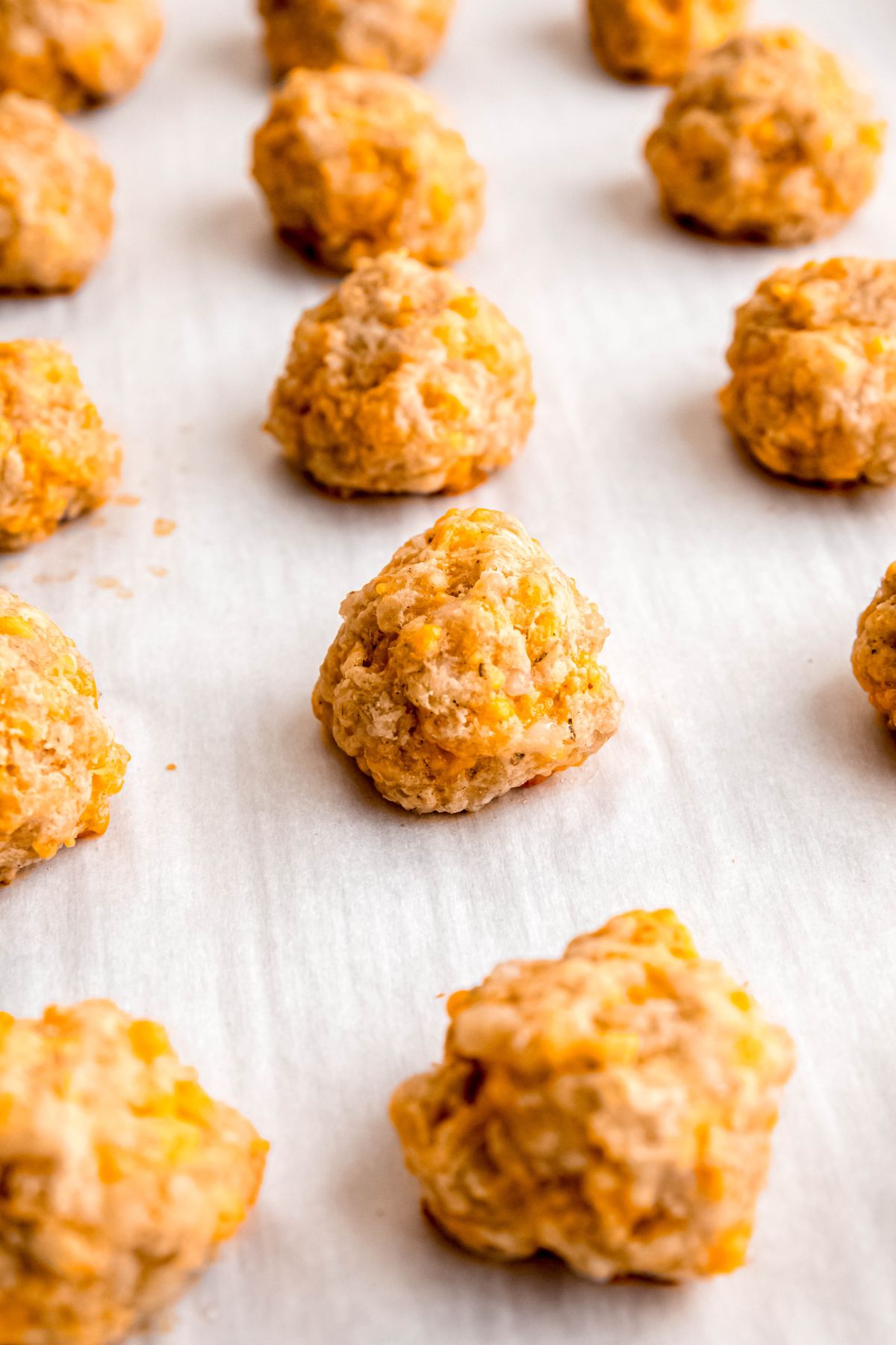 baked sausage balls on the parchment lined baking sheet after becoming slightly golden.