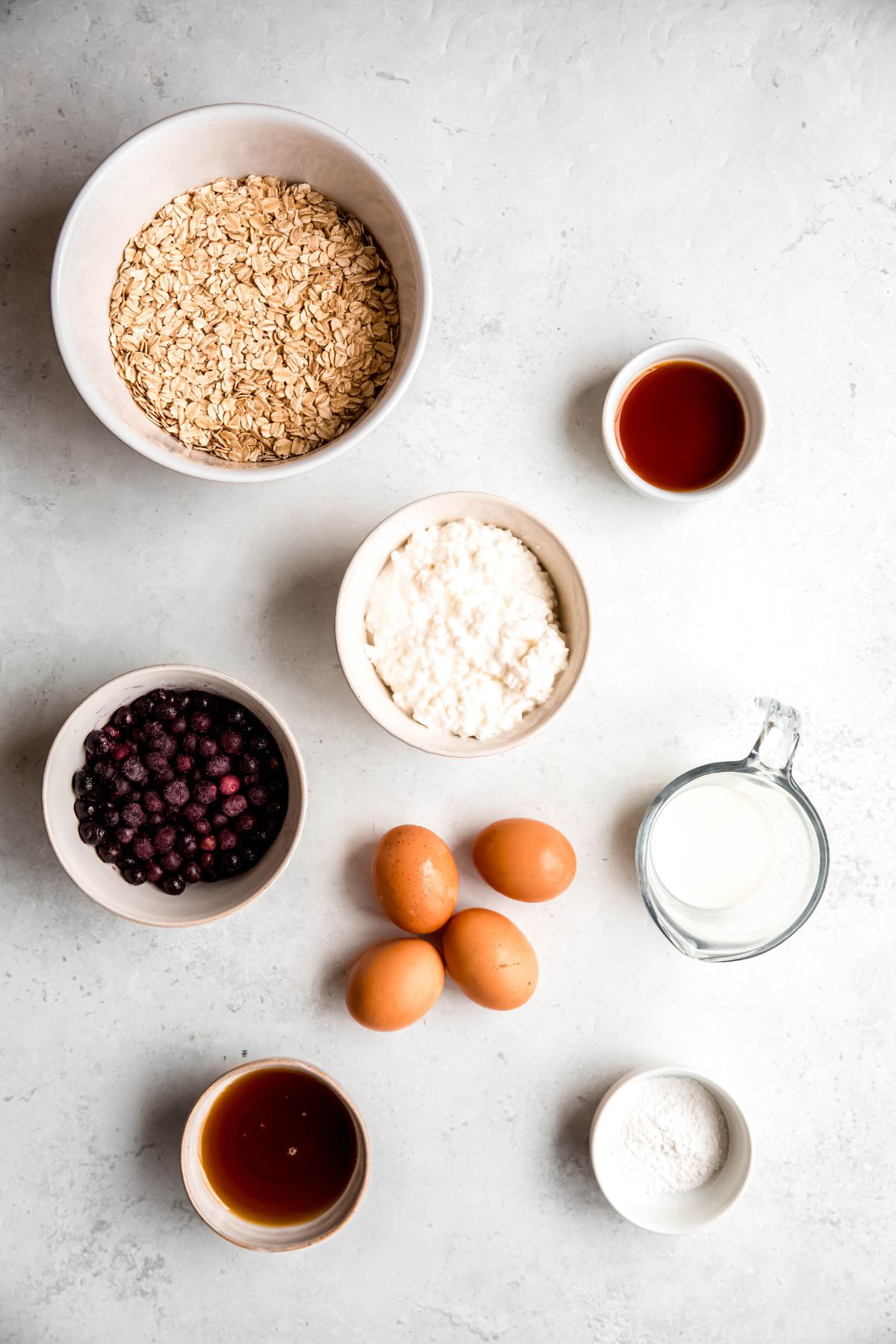 ingredients needed to make high protein blueberry baked oatmeal recipe measured out on a white table.