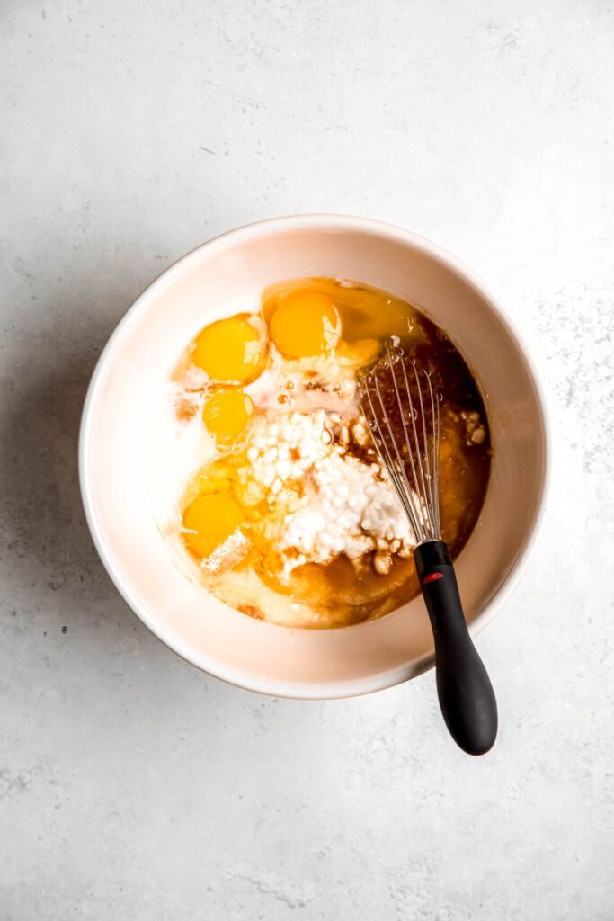 wet ingredients added to a mixing bowl with a whisk.