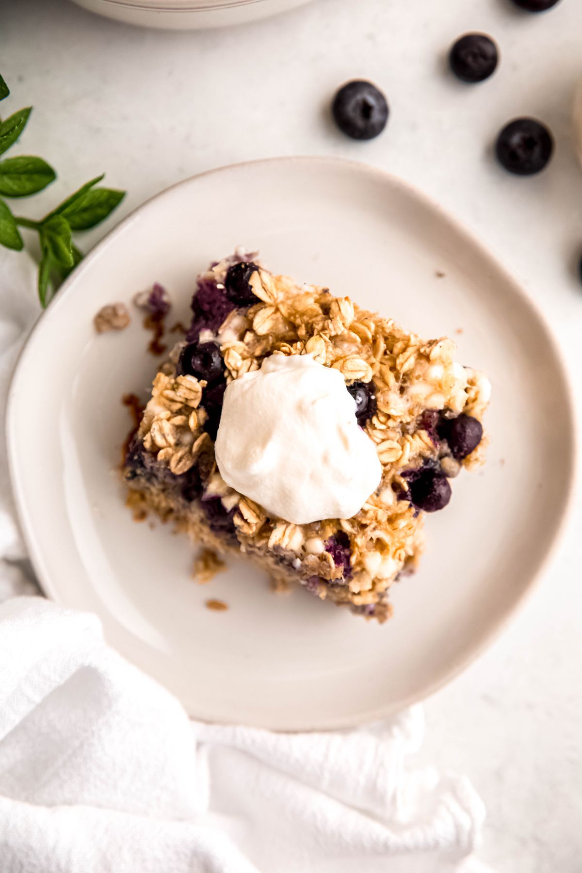 overhead shot of a slice of high protein baked blueberry oatmeal topped with a dollop of vanilla greek yogurt.