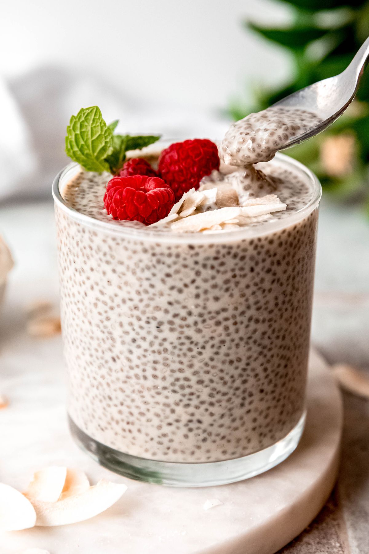 closeup shot of a silver spoon taking a bite of coconut protein chia pudding from the glass showing the thick, viscous, tapioca-like texture.