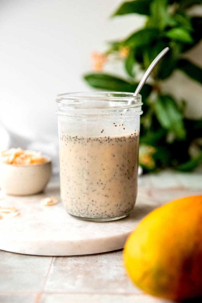 milk mixture after stirring in the chia seeds, maple syrup, and coconut extract with a silver spoon.