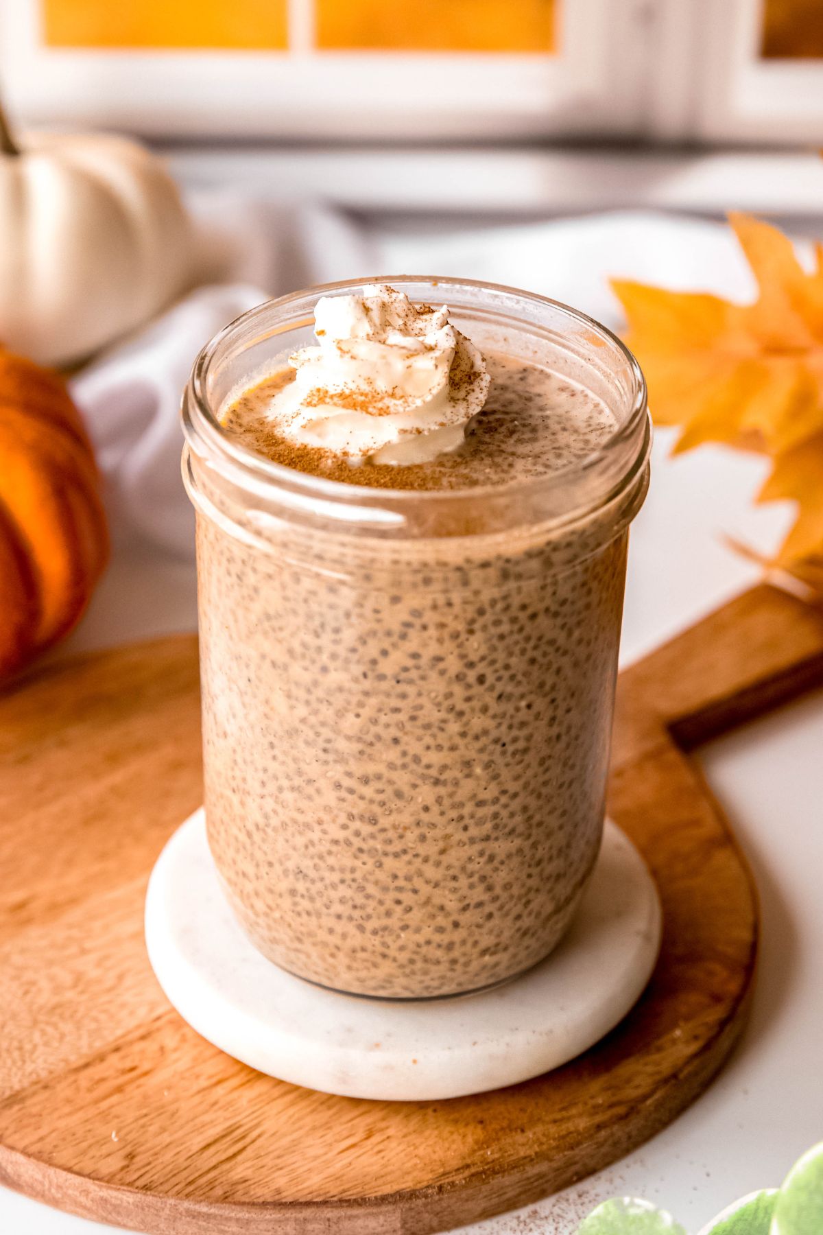 mason jar filled with pumpkin chia seed pudding topped with a dollop of whipped cream and a sprinkle of extra pumpkin pie spice.