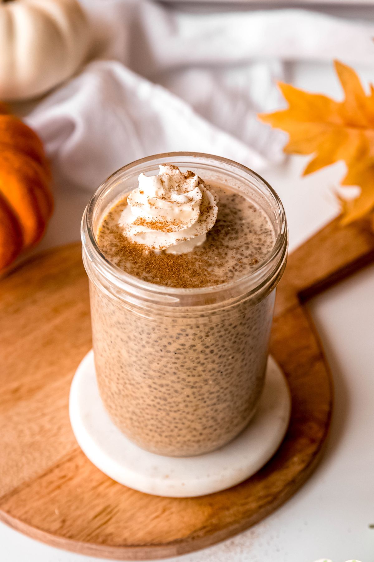 overhead 45 degree angle shot looking at the top of the pumpkin chia seed pudding topped with whipped cream and pumpkin pie spice.