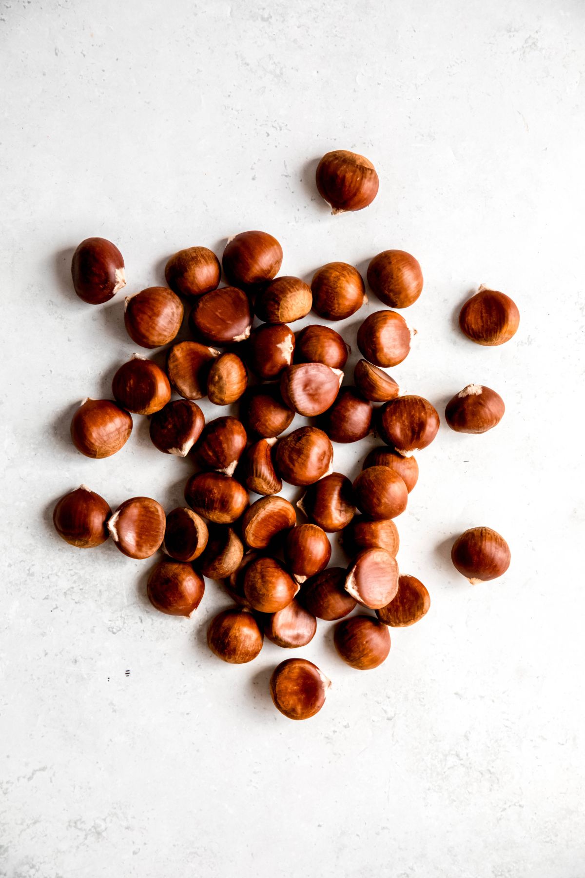 raw chestnuts in a pile on a white table.